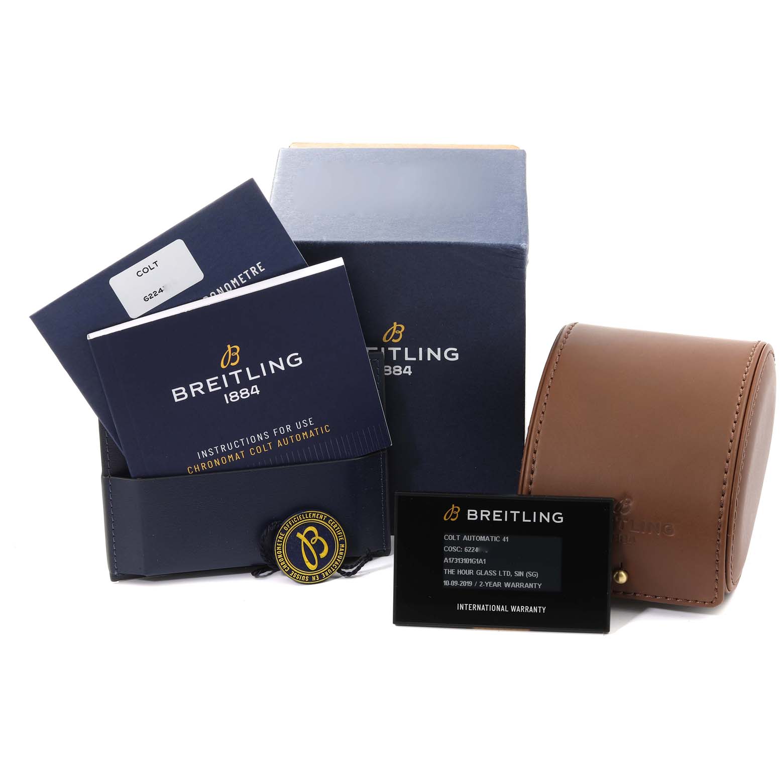 The image shows the Breitling Colt A17313 Men
s Stainless Steel White Dial A17313 Men
s Stainless Steel White Dial model watch packaging, manuals, warranty card, and a brown leather case.