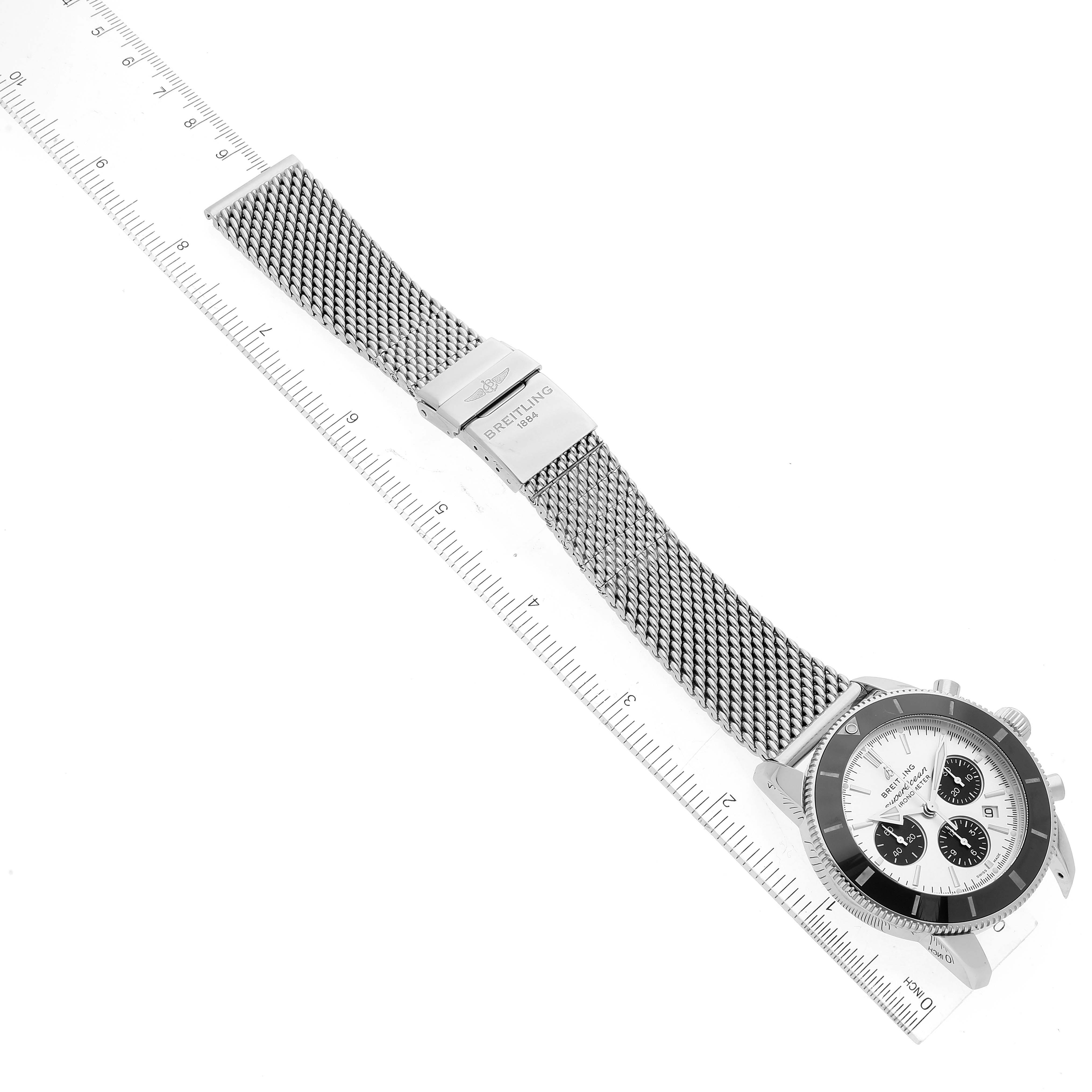 The image shows a top view of a Breitling Superocean AB0162 Men's Stainless Steel Silver Dial AB0162 Men's Stainless Steel Silver Dial watch with its mesh bracelet extended next to a ruler for scale.