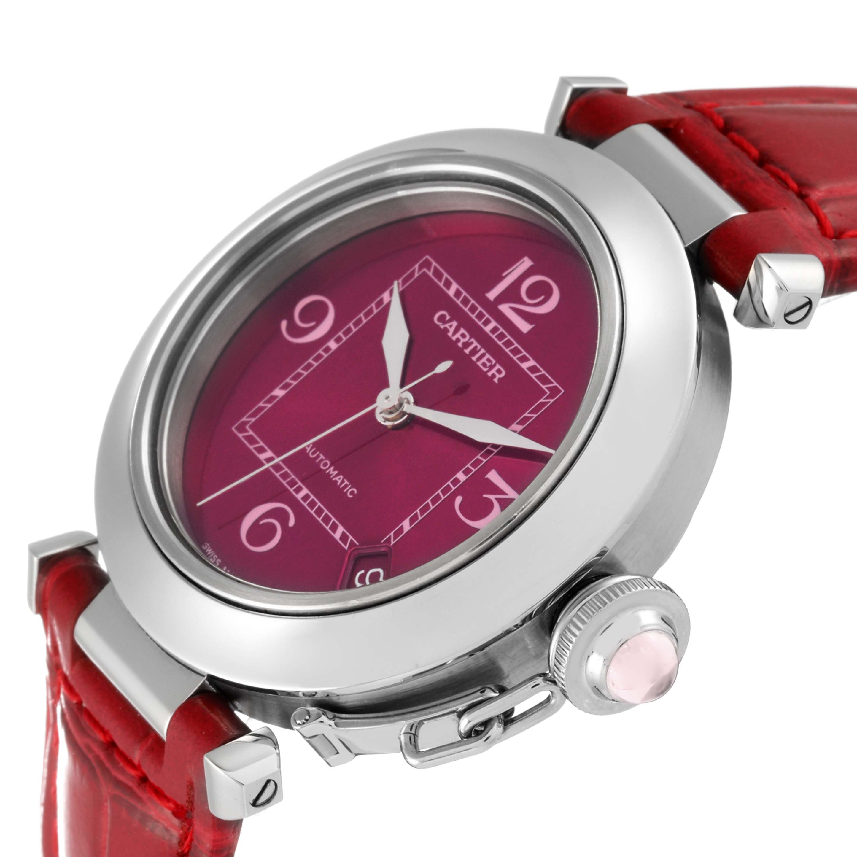 The image shows a close-up, angled view of the Cartier Pasha W3108299 Women's Stainless Steel Pink Dial W3108299 Women's Stainless Steel Pink Dial watch, highlighting the red dial, case, and crown with a pink cabochon.