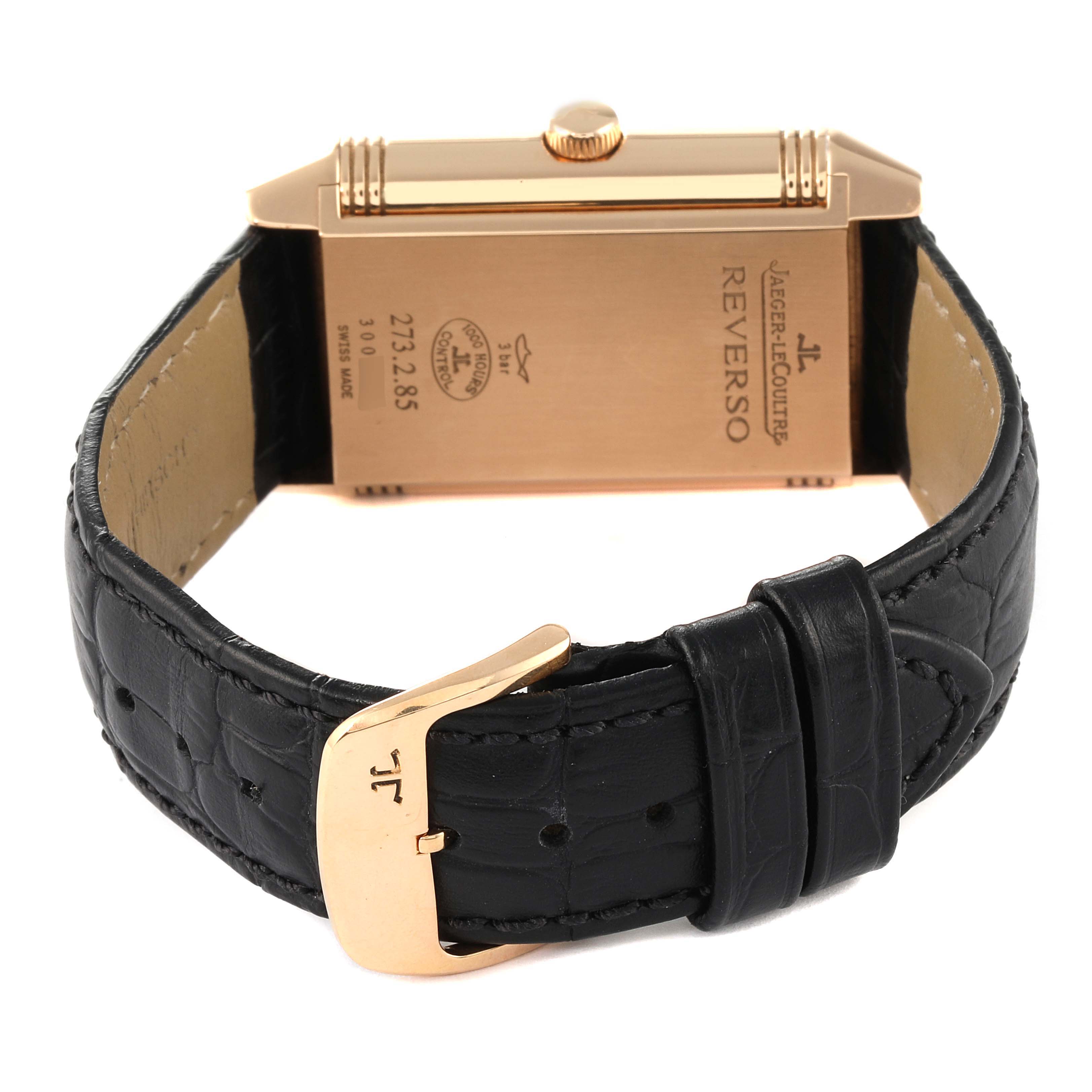The image shows the back of a Jaeger-LeCoultre Reverso watch, featuring its leather strap and buckle.