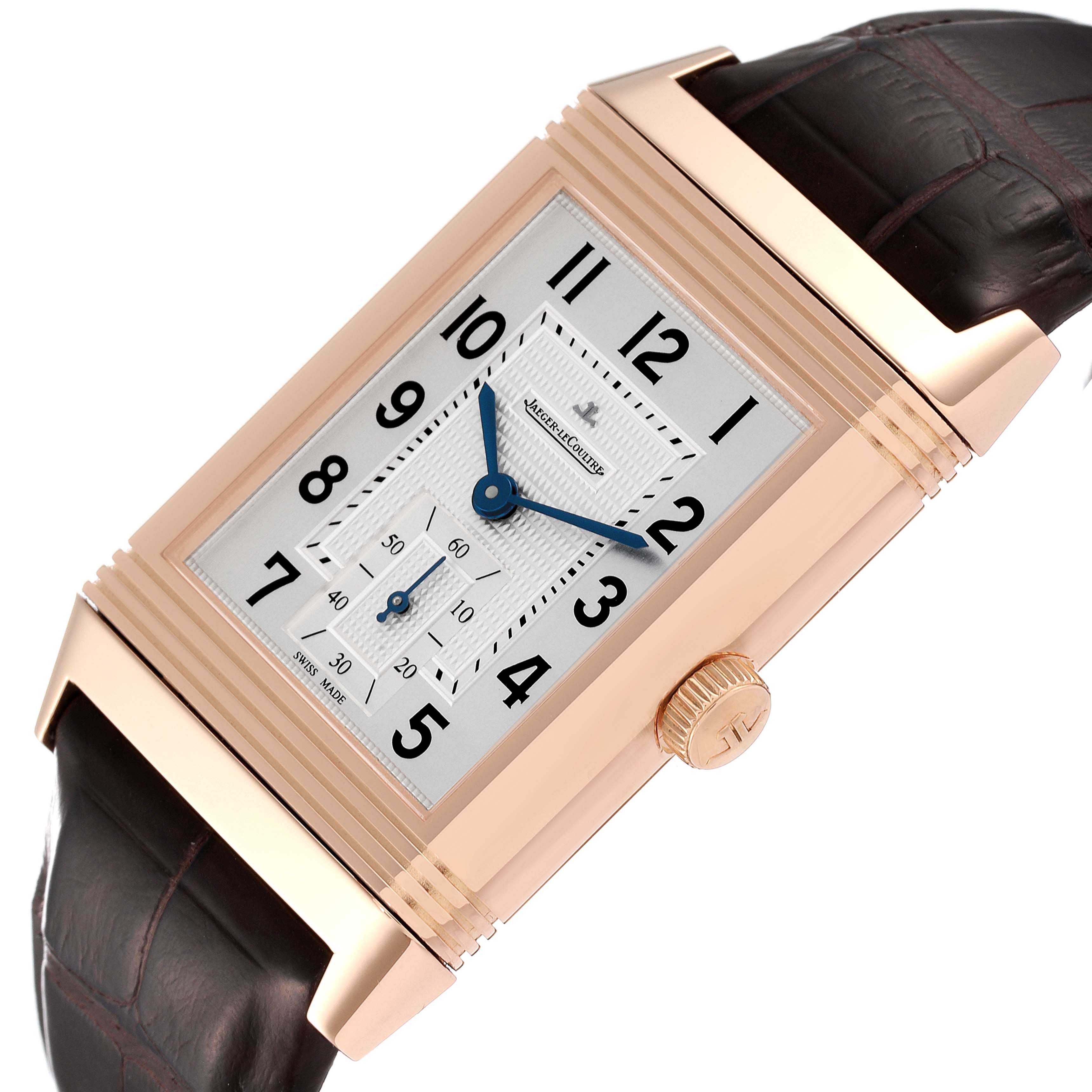 The Jaeger-LeCoultre Reverso watch is shown at an angle emphasizing its face, crown, and brown leather strap.