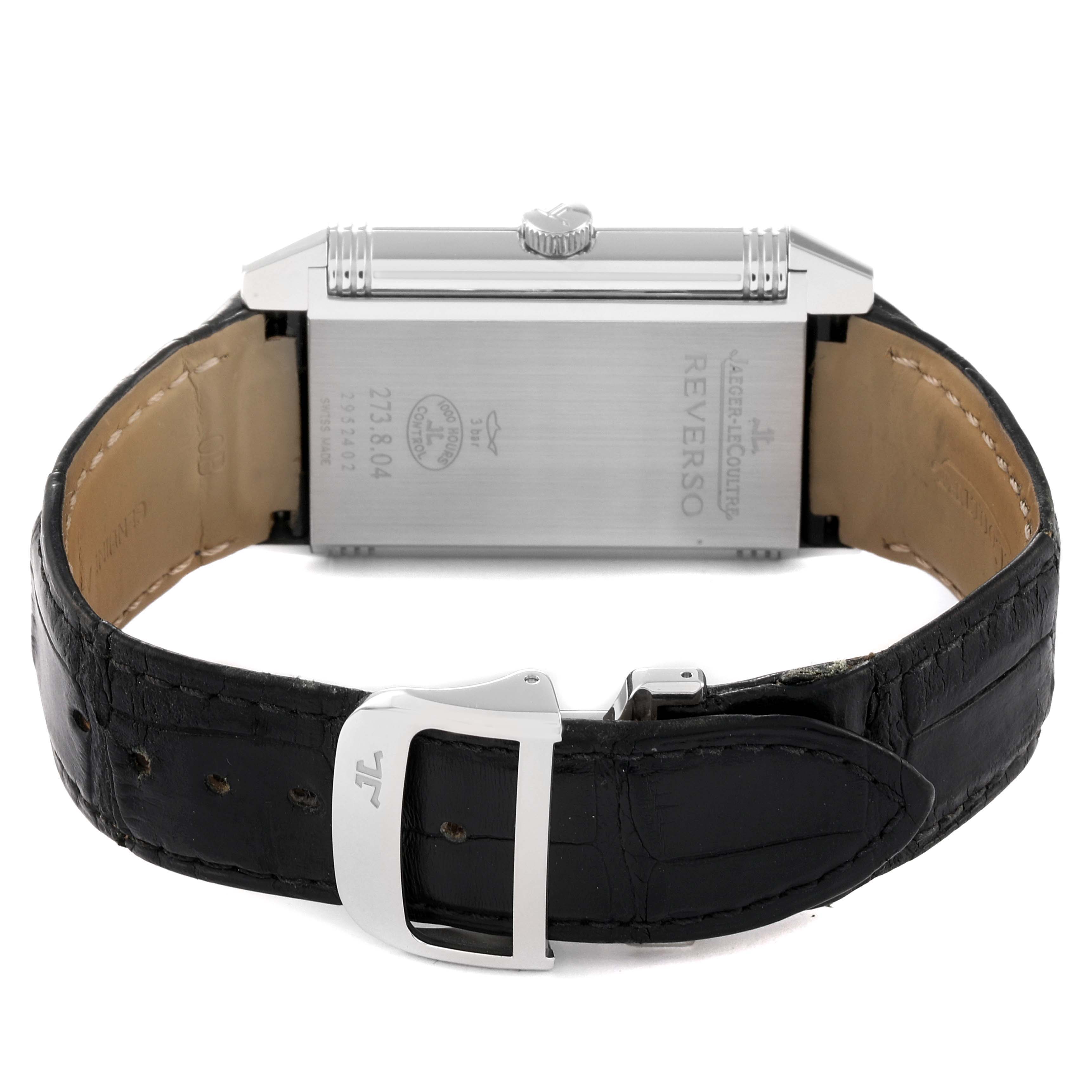 The image shows a rear view of a Jaeger-LeCoultre Reverso watch, highlighting its clasp, leather strap, and back case.