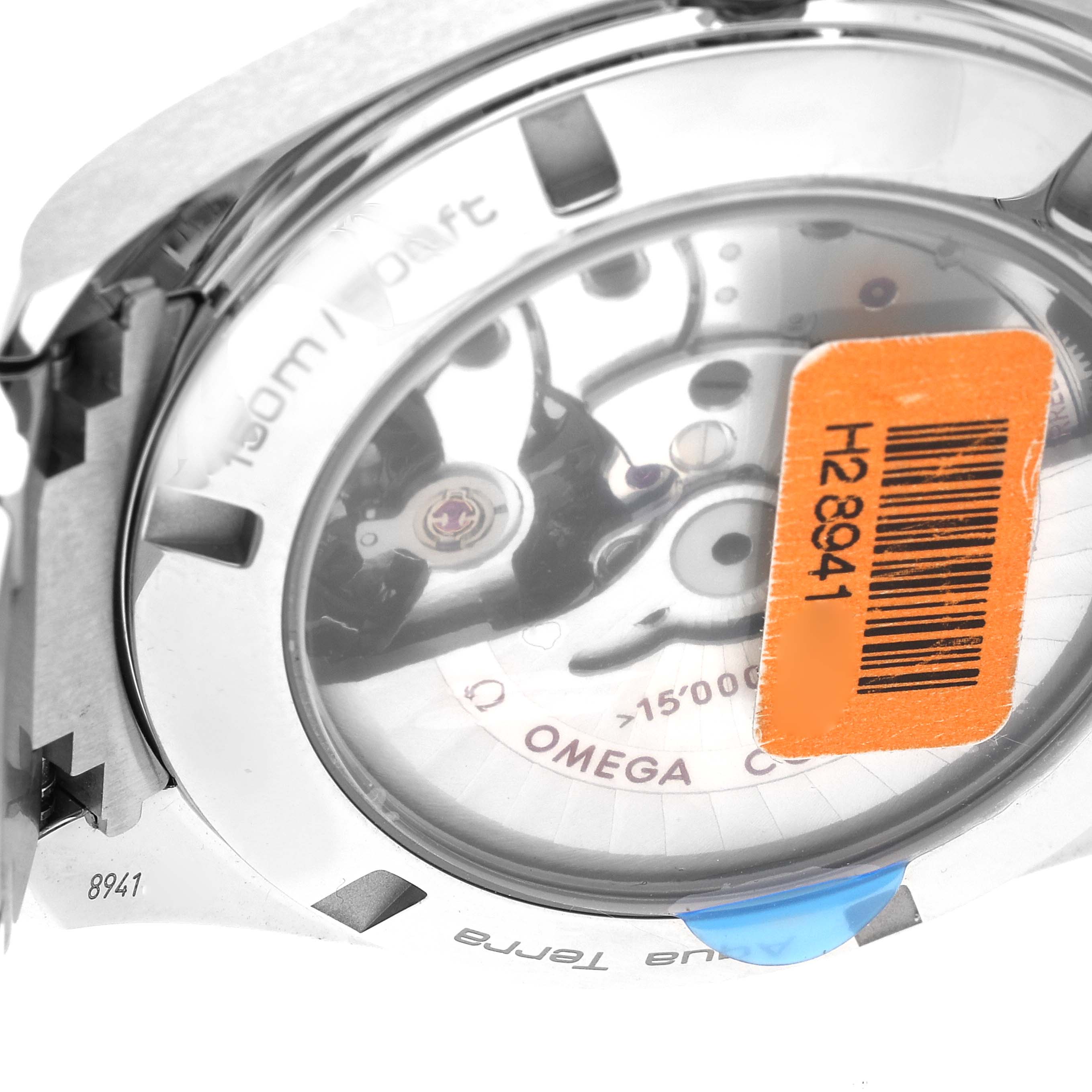 The image shows the back of an Omega Aqua Terra 231.10.42.21.01.002 Men's Stainless Steel Black Dial 231.10.42.21.01.002 Men's Stainless Steel Black Dial watch, focusing on the movement and transparent case back with an orange sticker.