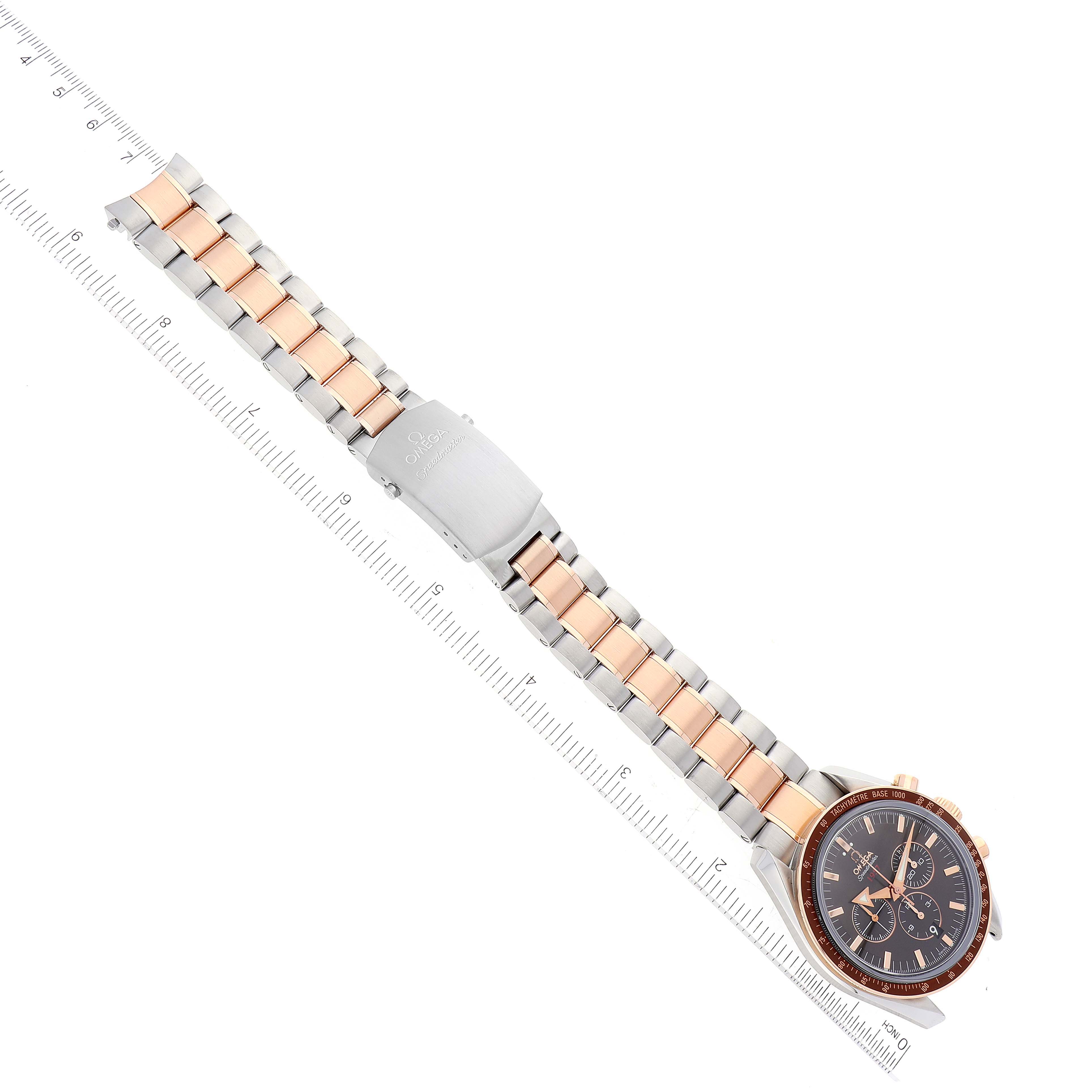 The image shows an Omega Speedmaster 321.90.42.50.13.001 Men's Steel and Gold (two tone) Brown Dial 321.90.42.50.13.001 Men's Steel and Gold (two tone) Brown Dial watch positioned diagonally, highlighting its face, bezel, and bracelet with a clasp.