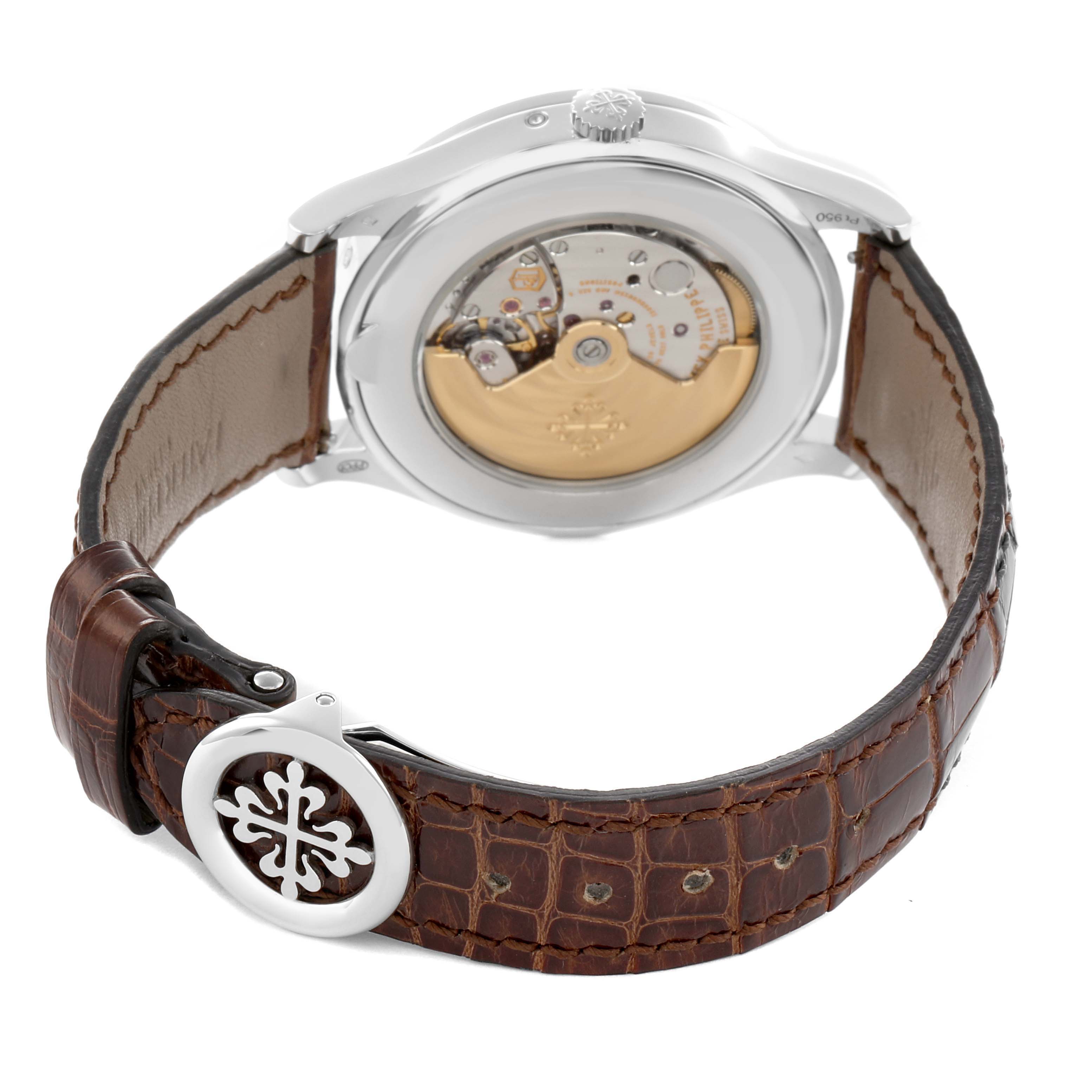 The image shows the back view of a Patek Philippe Complications 5496P-014 Men's Platinum Brown Dial, highlighting the movement and leather strap with a decorative clasp.