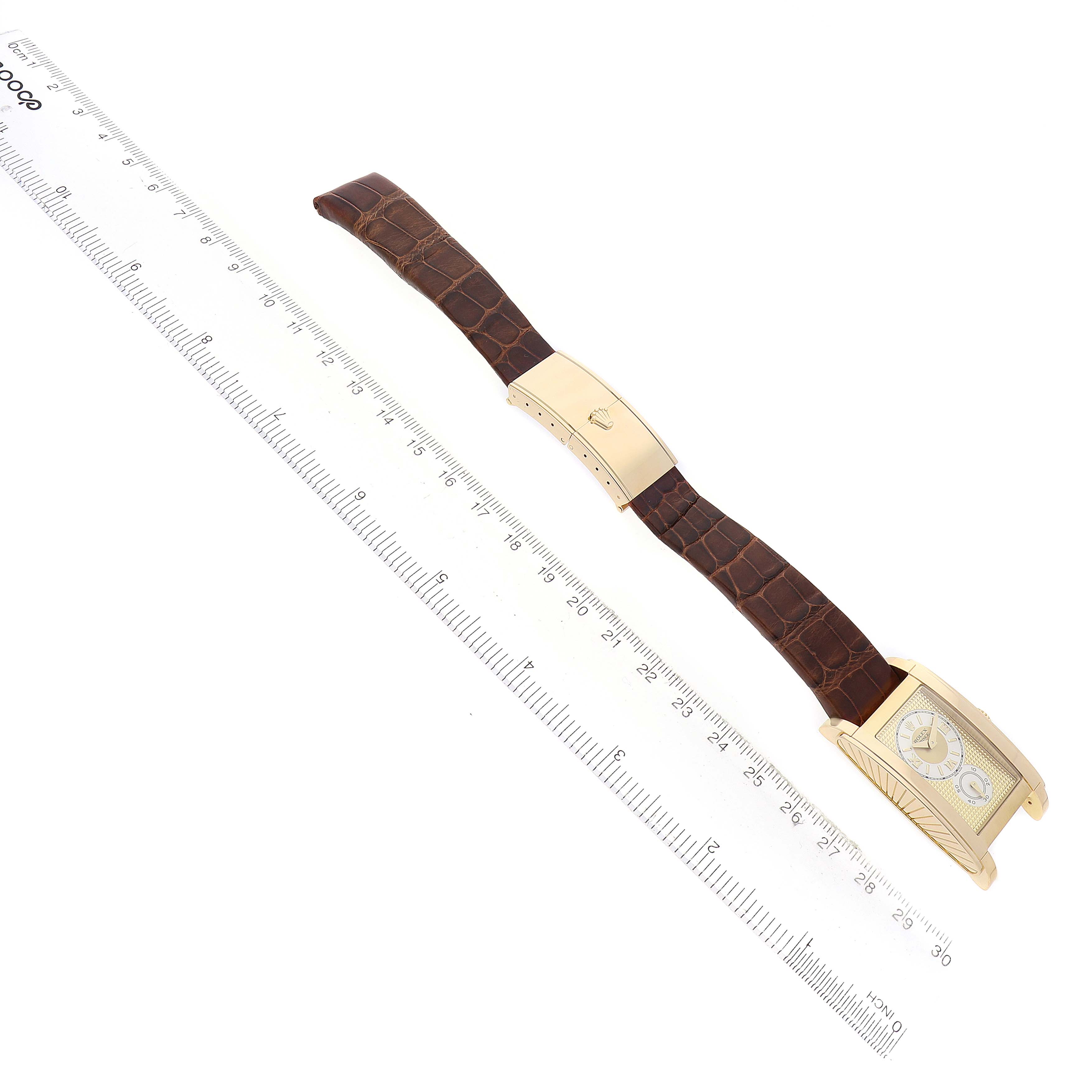 The Rolex Cellini 5440 Men's Yellow Gold Champagne Dial watch is shown diagonally with a brown strap, clasp, and partial view of the rectangular watch face.