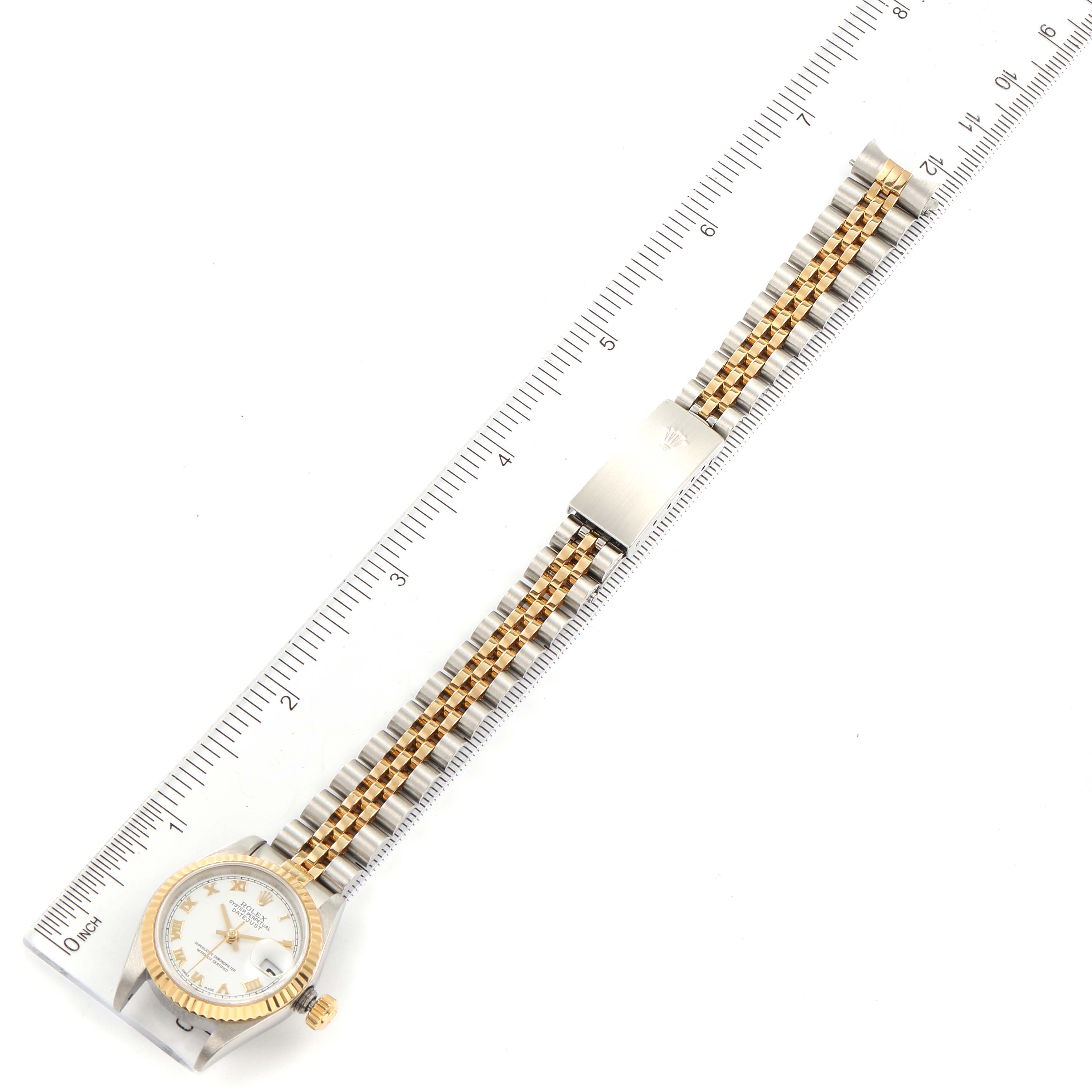 This image shows the Rolex Datejust 79173 Women's Steel and Gold (two tone) White Dial 79173 Women's Steel and Gold (two tone) White Dial watch laid flat next to a ruler, showcasing its full bracelet and face from an overhead angle.