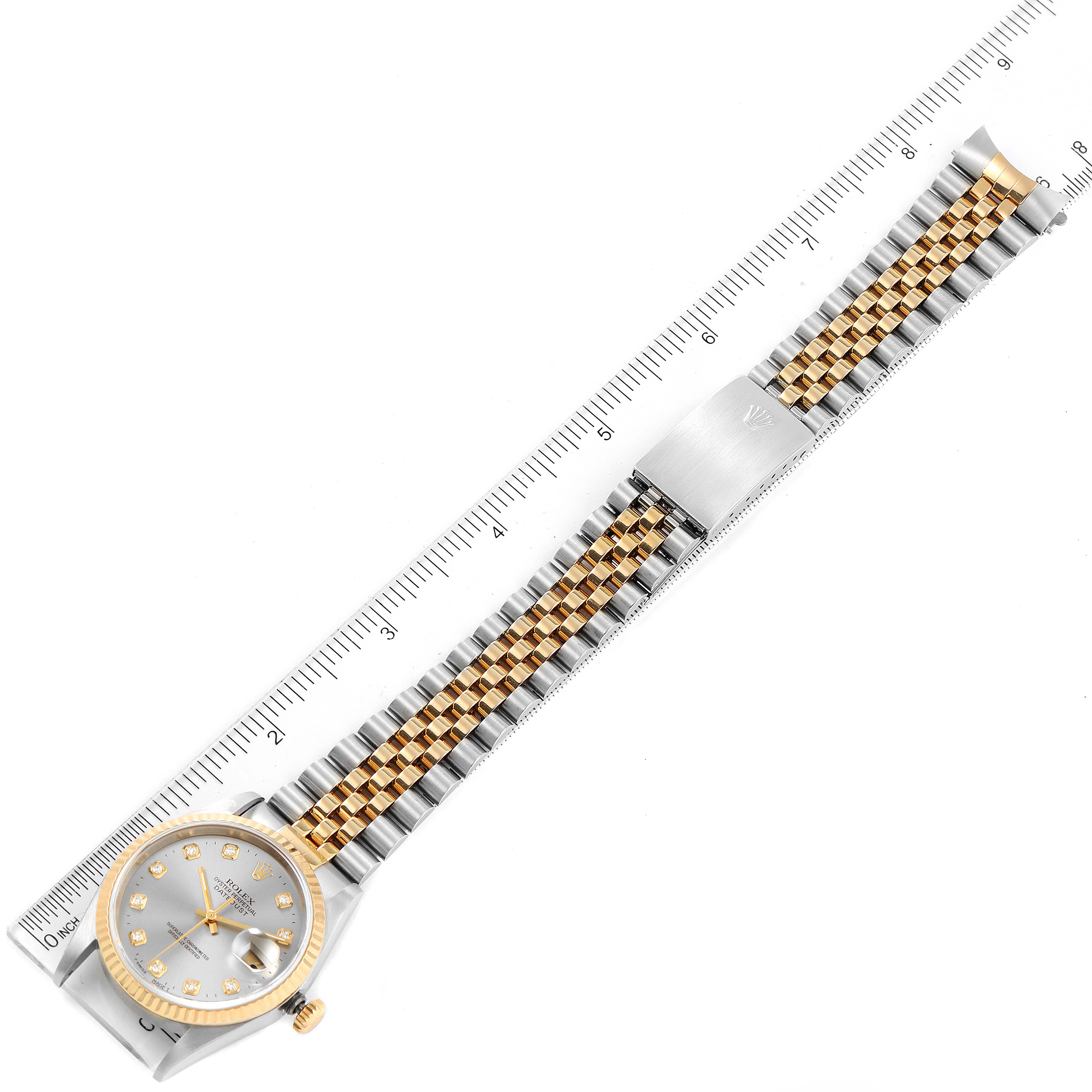 The image shows a Rolex Datejust 16233 Men
s Steel and Gold (two tone) Grey Dial 16233 Men
s Steel and Gold (two tone) Grey Dial watch laid flat with a ruler, displaying its face, bracelet, and clasp.