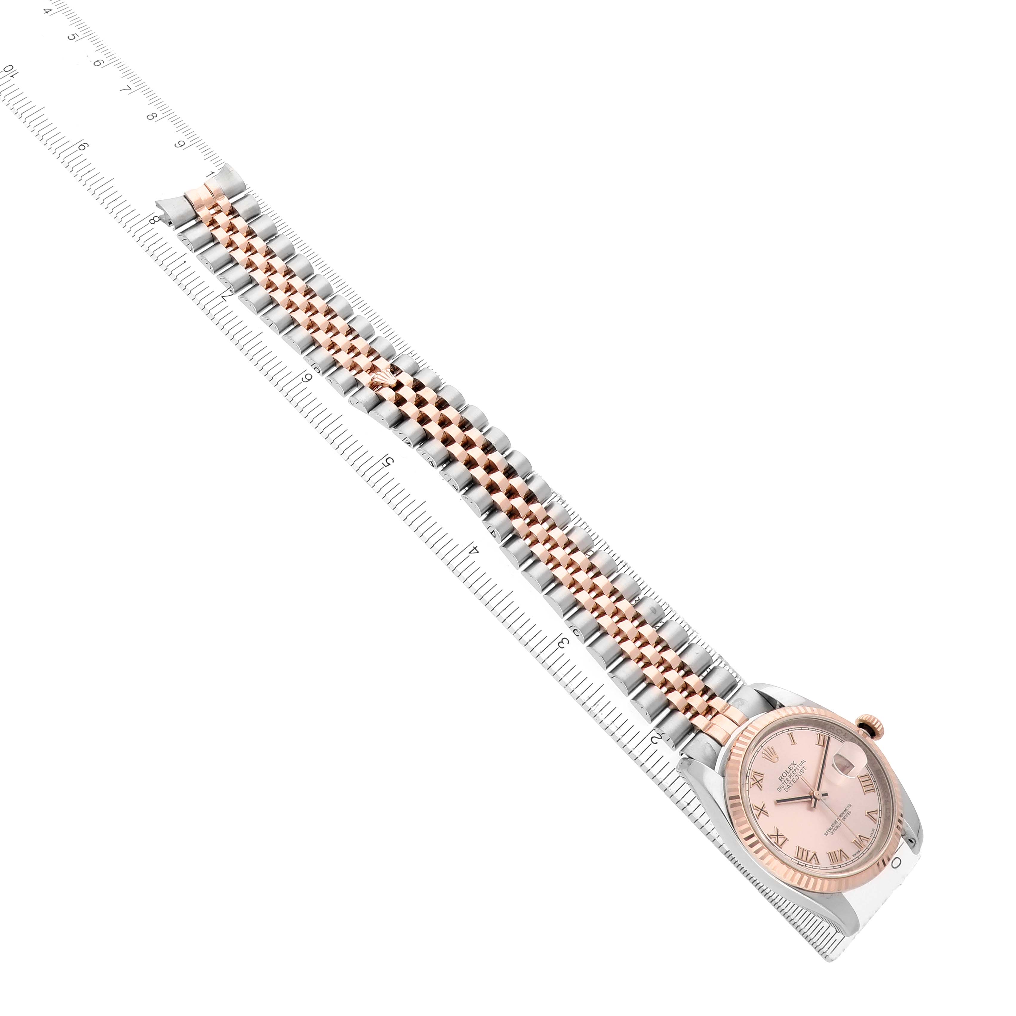 The Rolex Datejust 116231 Men
s Steel and Gold (two tone) Pink Dial watch is shown diagonally, highlighting its two-tone bracelet and pink dial near a clear ruler for scale.