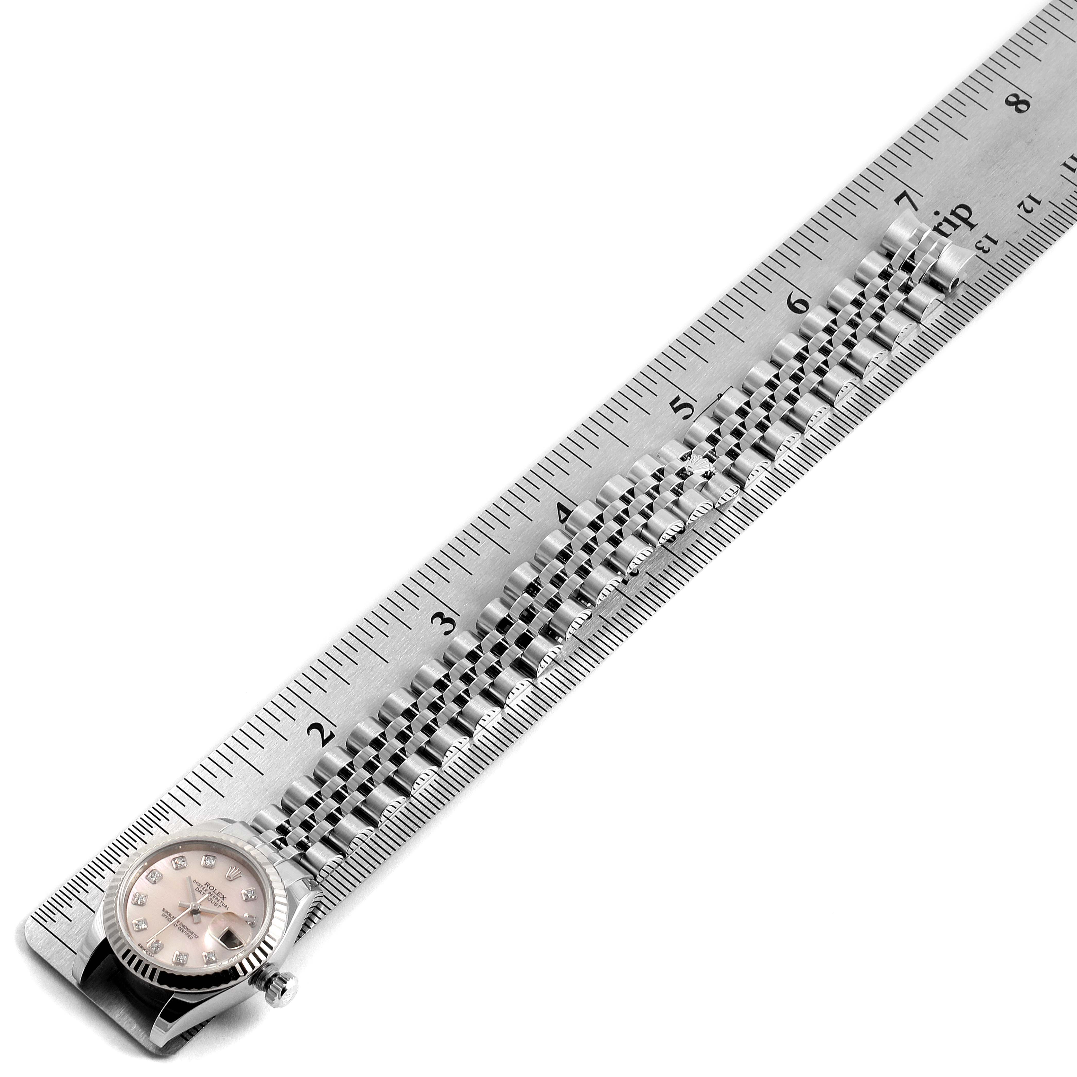 The image shows the Rolex Datejust 179174 Women's Stainless Steel Mother of Pearl Dial 179174 Women's Stainless Steel Mother of Pearl Dial watch from a top-down angle, with a focus on its face and metal bracelet beside a ruler.