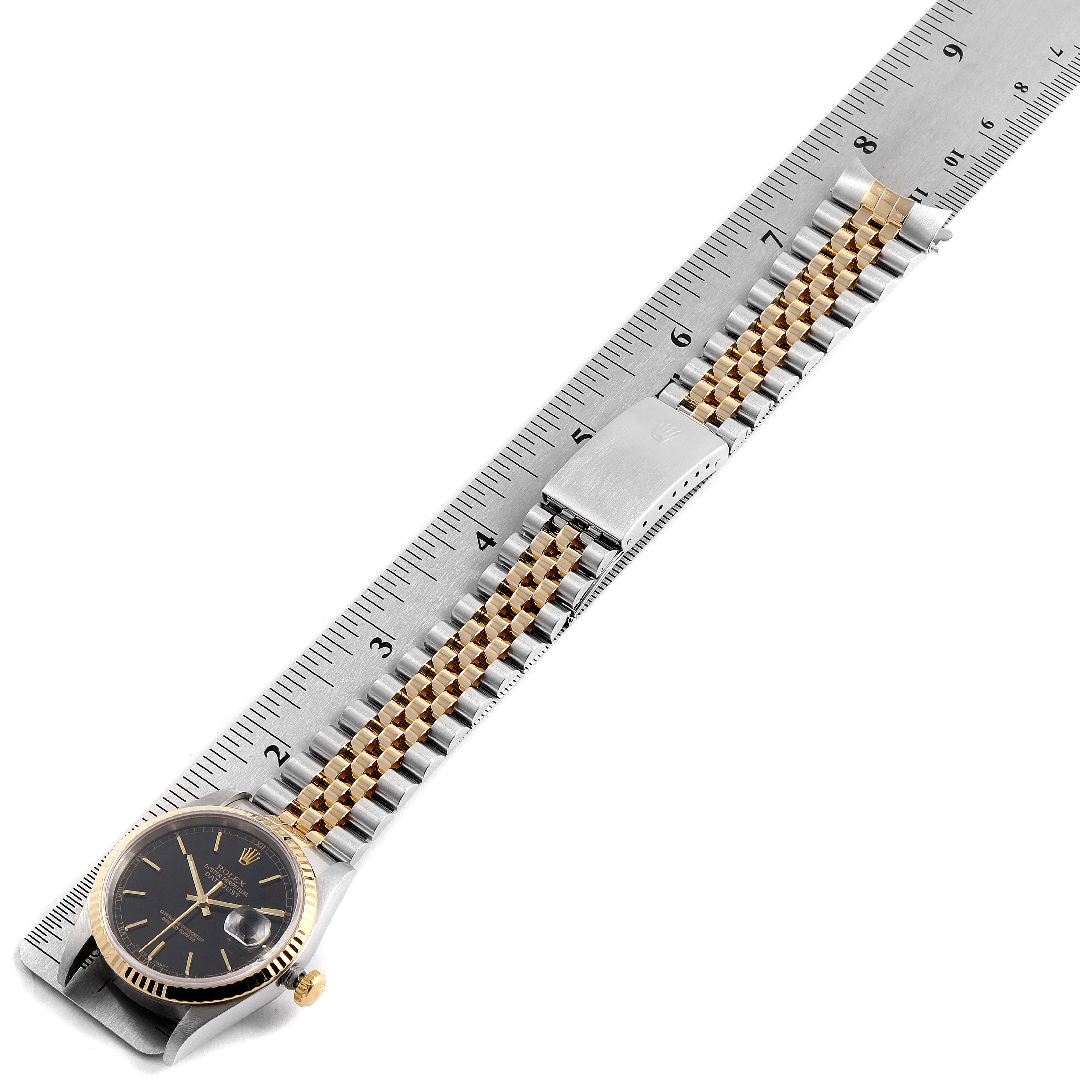 This image shows the Rolex Datejust 16233 Men's Steel and Gold (two tone) Black Dial 16233 Men's Steel and Gold (two tone) Black Dial model watch laid flat, focusing on the face, band, clasp, and ruler for size reference.