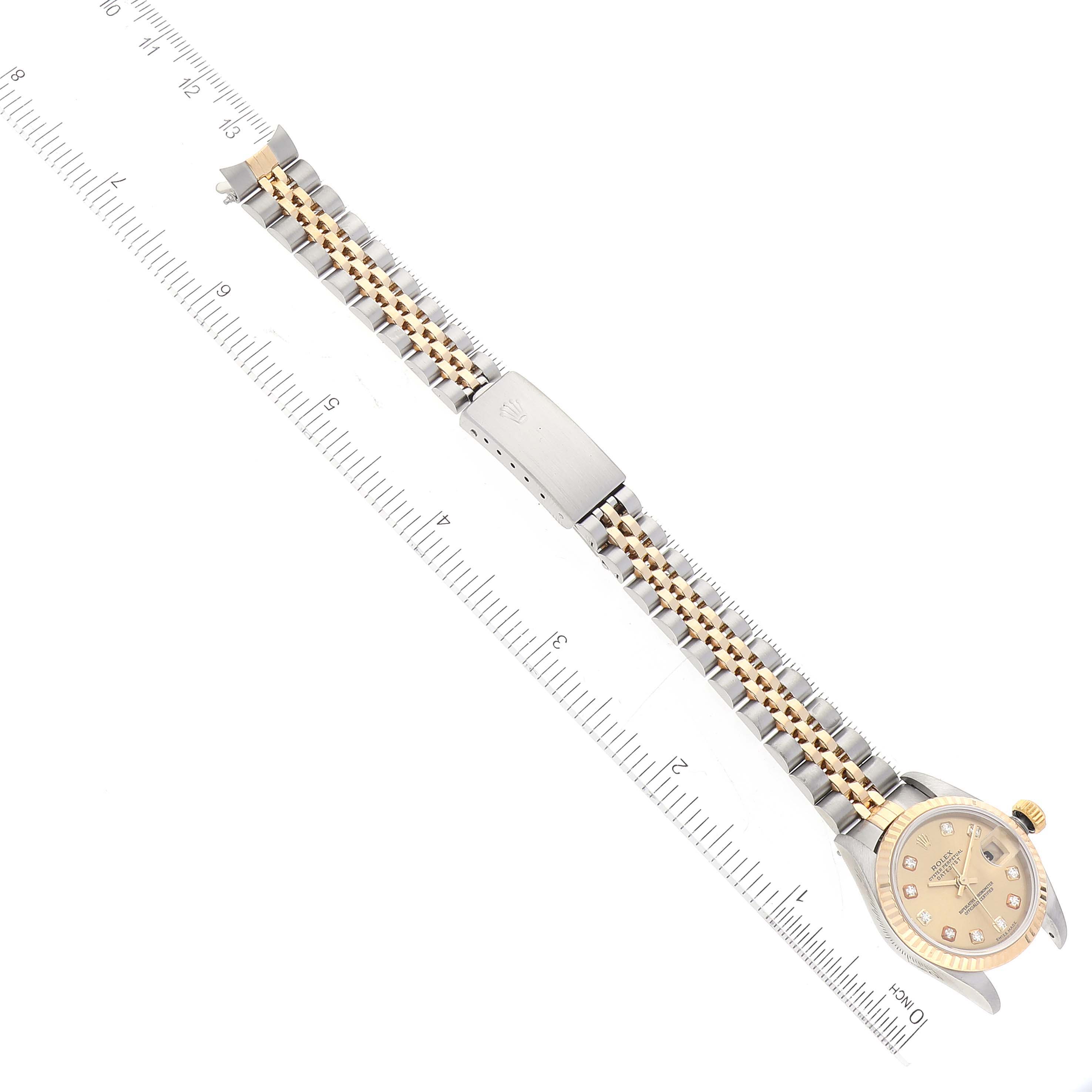 The image shows a top-down view of a Rolex Datejust 79173 Women's Steel and Gold (two tone) Champagne Dial 79173 Women's Steel and Gold (two tone) Champagne Dial watch, including its bracelet and clasp, with a ruler for scale.