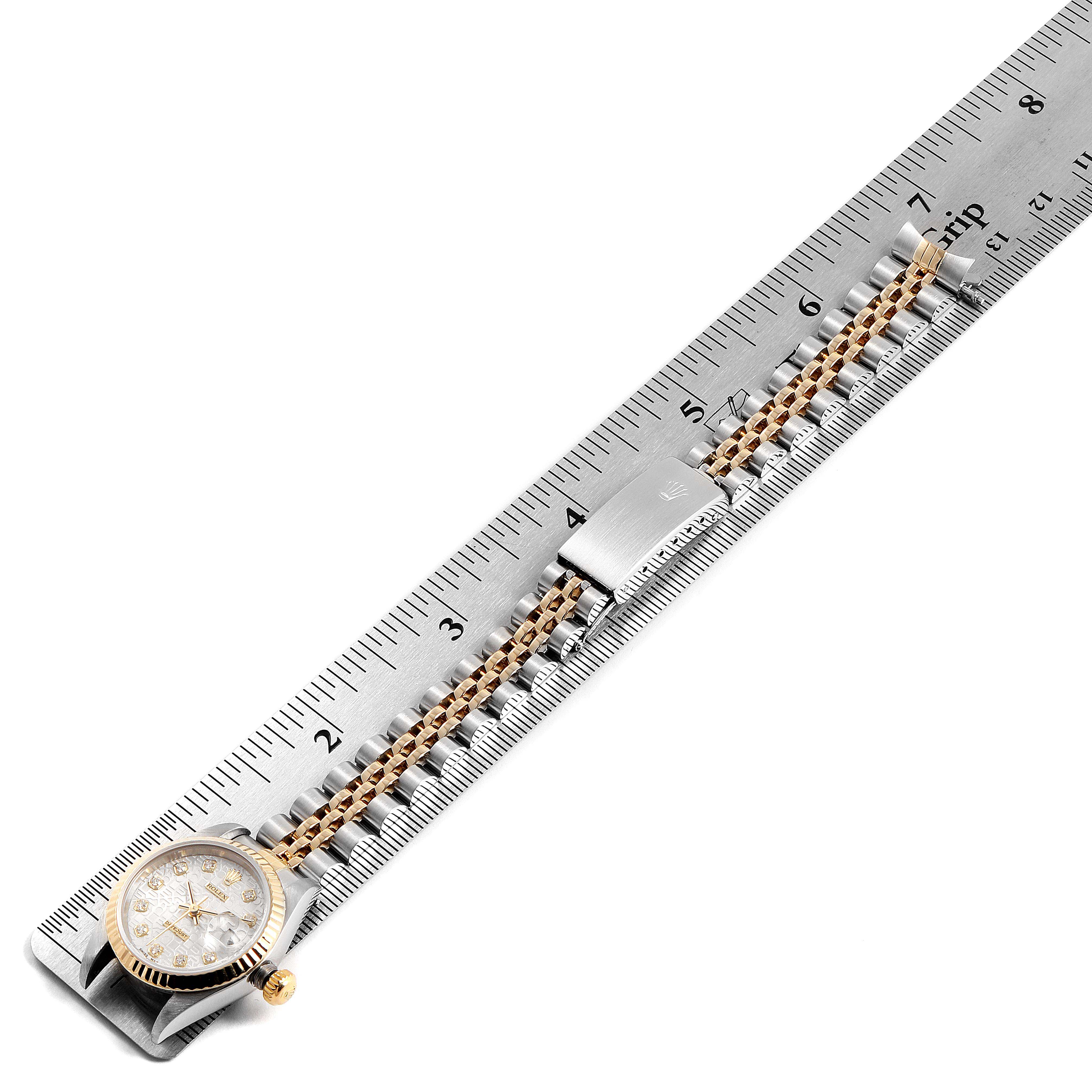 The image shows a top-down view of the Rolex Datejust 79173 Women's Stainless Steel Silver Dial 79173 Women's Stainless Steel Silver Dial watch, highlighting its dial, crown, and bracelet laid against a ruler.