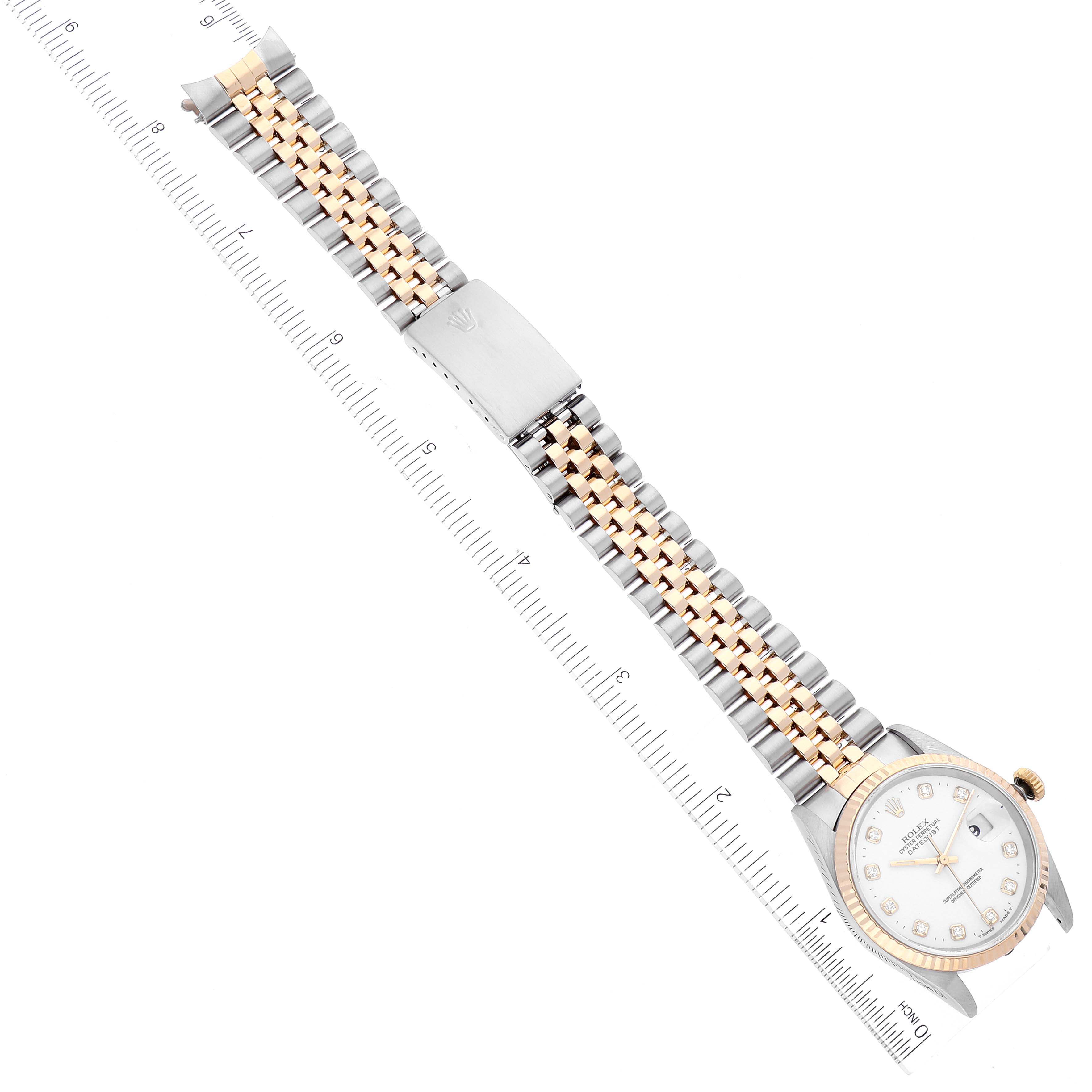 This is an overhead view of a Rolex Datejust 16233 Men's Steel and Gold (two tone) White Dial 16233 Men's Steel and Gold (two tone) White Dial watch showing the face, band, and clasp with a ruler for scale.