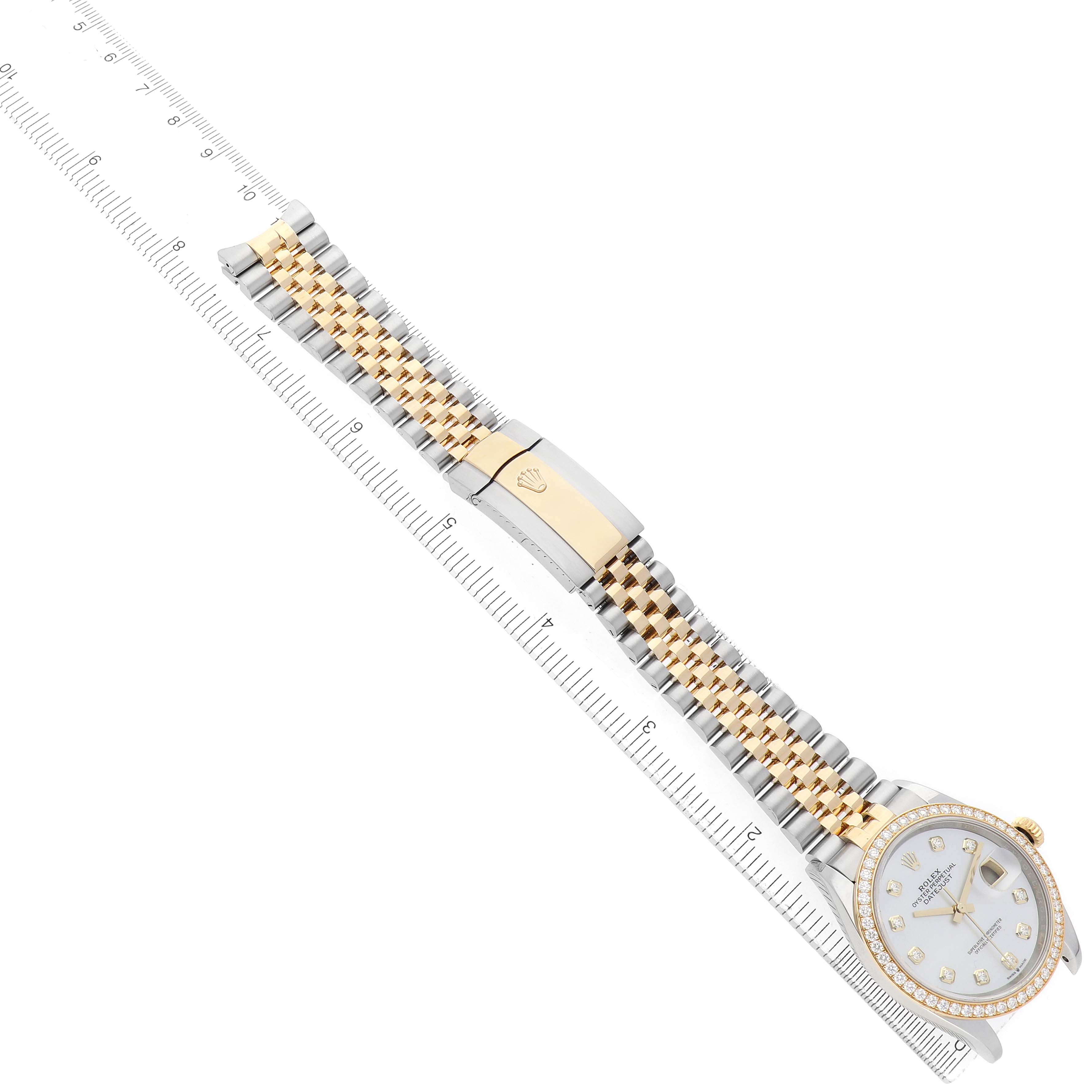 The Rolex Datejust 126283 Men's Steel and Gold (two tone) Mother of Pearl Dial watch is shown at an angled top view, displaying the face, bracelet, and clasp with a ruler beside it.