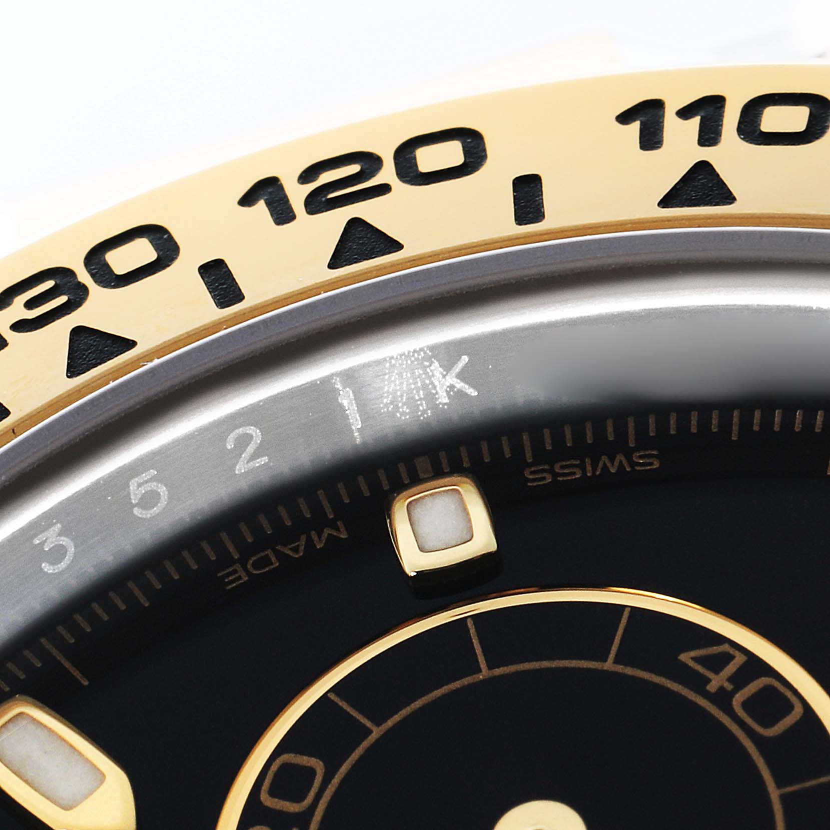 The image shows a close-up of the bezel and part of the dial on a Rolex Daytona 116503 Men's Steel and Gold (two tone) Black Dial, highlighting the tachymetric scale.