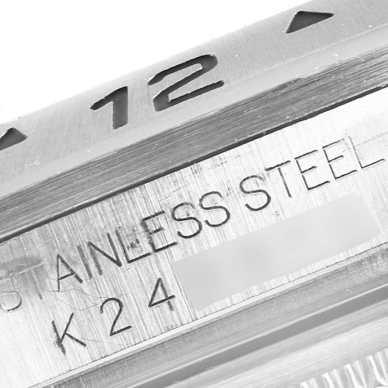 This image shows a close-up of the bezel and part of the case of a Rolex Explorer 16570 Men
s Stainless Steel Black Dial 16570 Men
s Stainless Steel Black Dial watch, highlighting the "12" marker and "Stainless Steel" engraving.