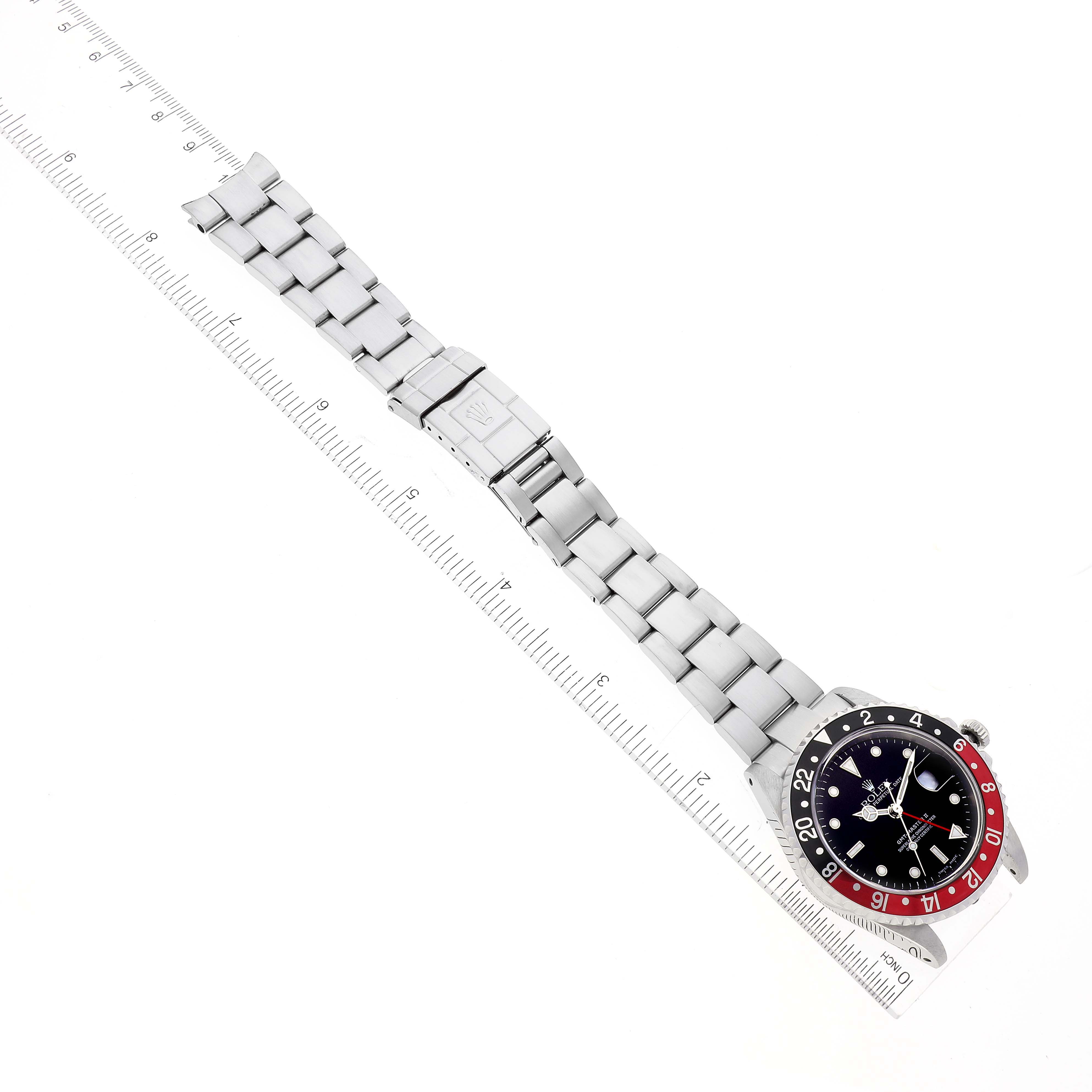 The Rolex GMT-Master 16710 Men's Stainless Steel Black Dial 16710 Men's Stainless Steel Black Dial watch is shown flat with its bracelet extended alongside a ruler.