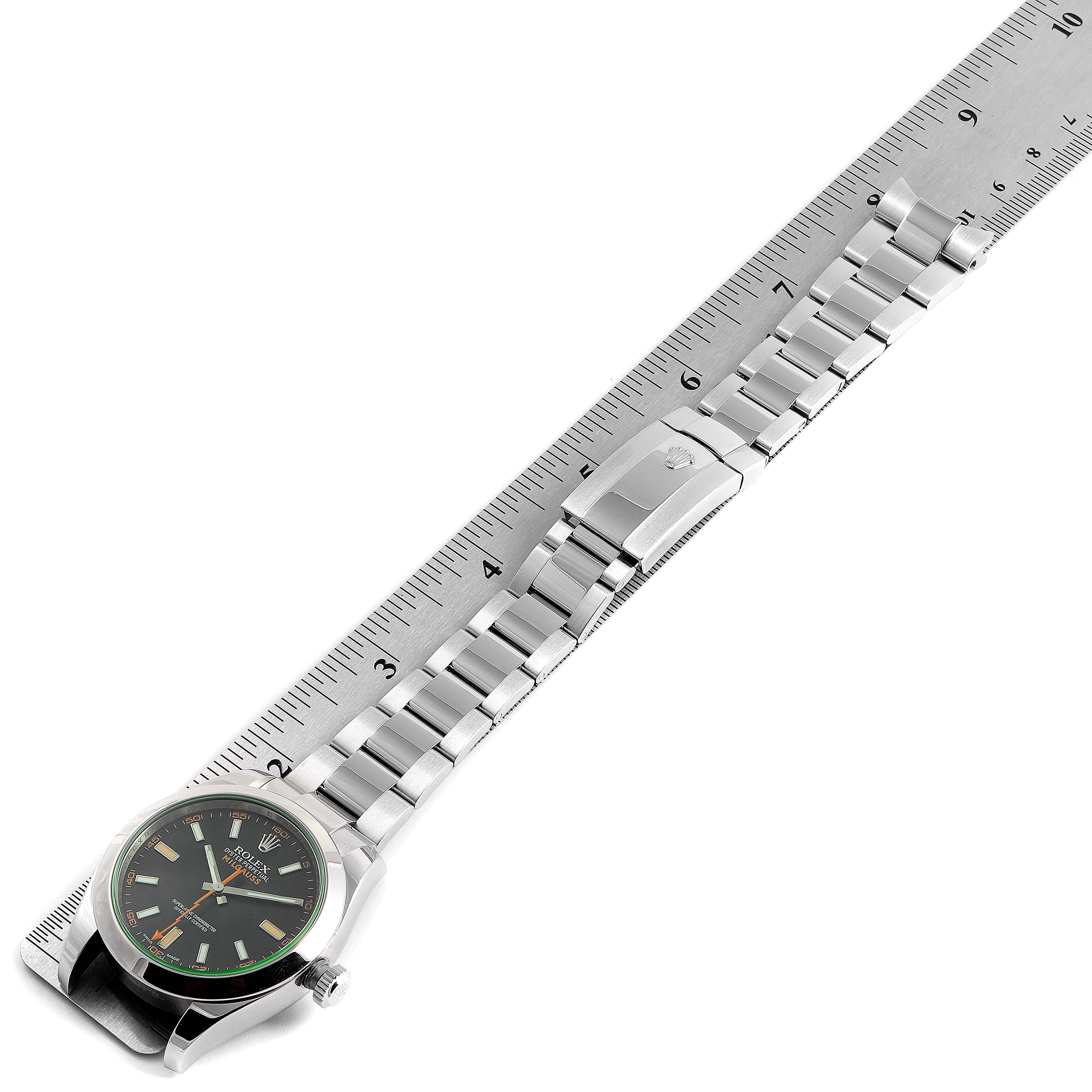 The Rolex Milgauss 116400V Men's Stainless Steel Black Dial 116400V Men's Stainless Steel Black Dial watch is shown from a top-down angle, displaying the face, bracelet, and clasp aligned with a ruler.