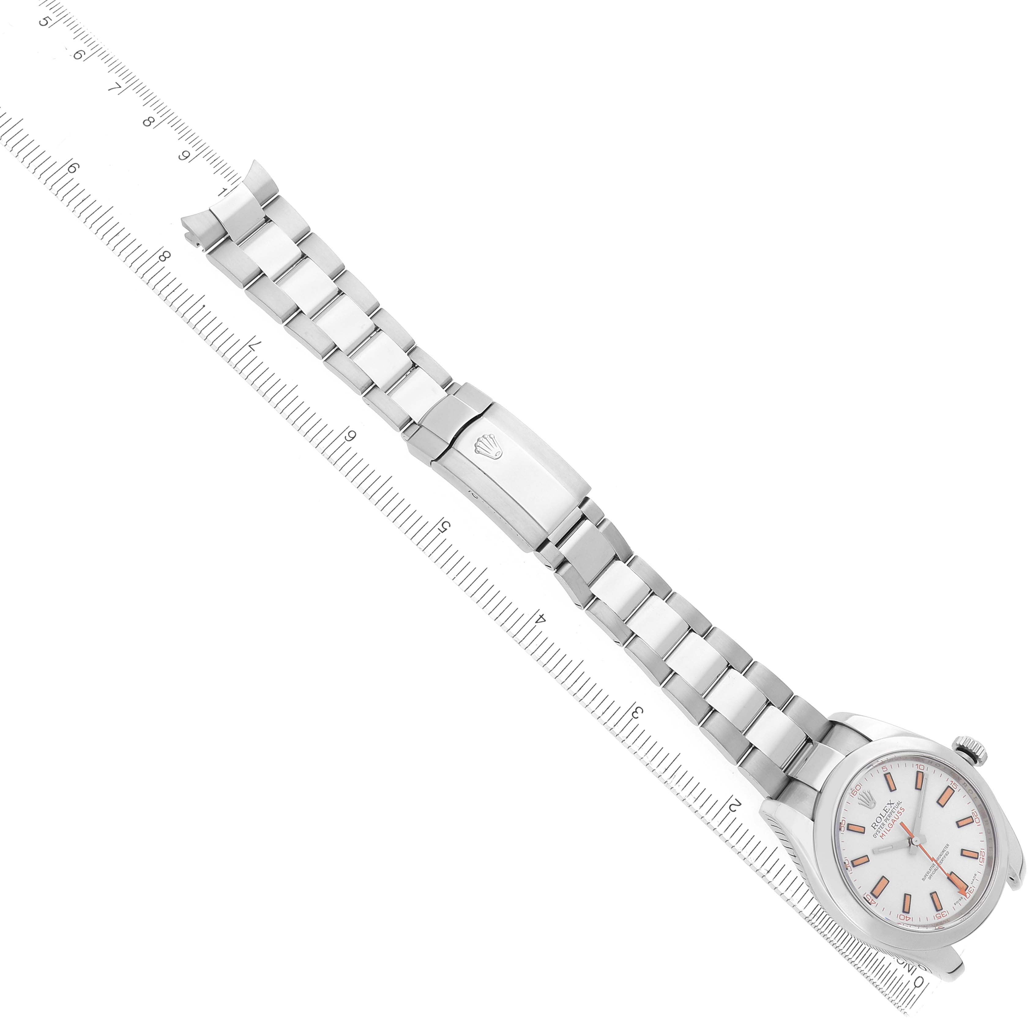 The Rolex Milgauss 116400 Men's Stainless Steel White Dial watch is displayed at an angle showing the full bracelet, clasp, and dial alongside a measuring ruler.