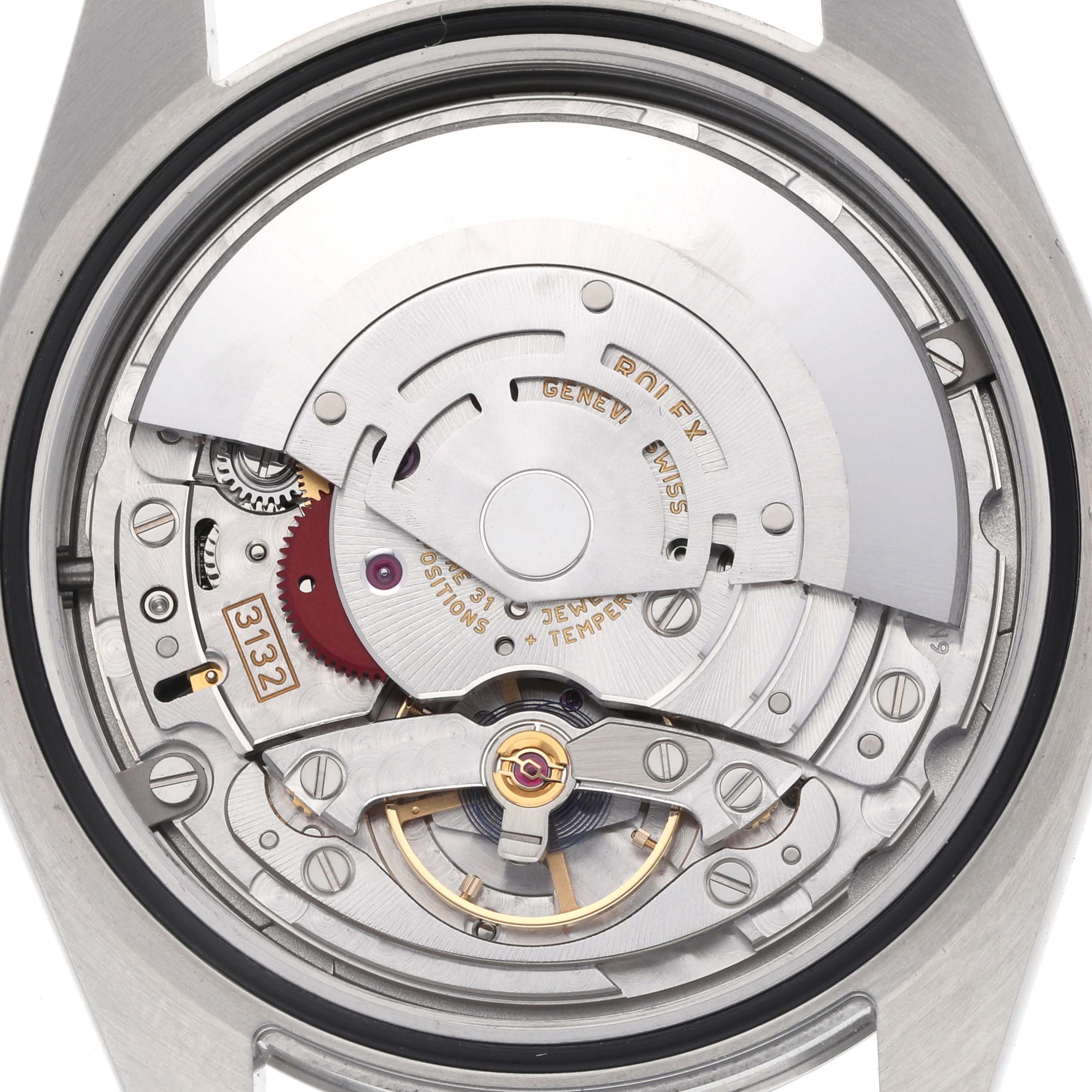 The image shows the movement of a Rolex Oyster Perpetual 114300 Men's Stainless Steel Silver Dial watch, viewed from the back, highlighting the rotor and intricate mechanism.