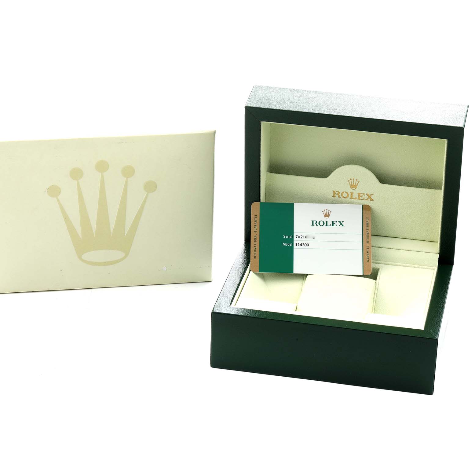 The image shows the open green box of a Rolex Oyster Perpetual 114300 Men
s Stainless Steel Blue Dial, with a warranty card and logo, including an exterior sleeve.
