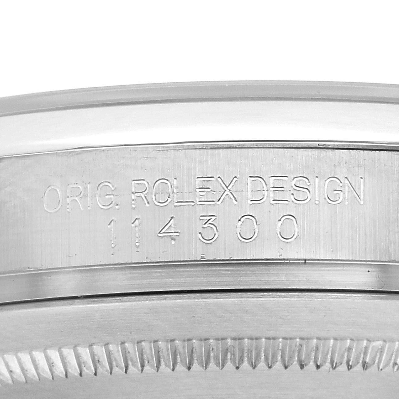 The image shows a close-up of the side casing of a Rolex Oyster Perpetual 114300 Men
s Stainless Steel Blue Dial with the model number 114300 engraved.