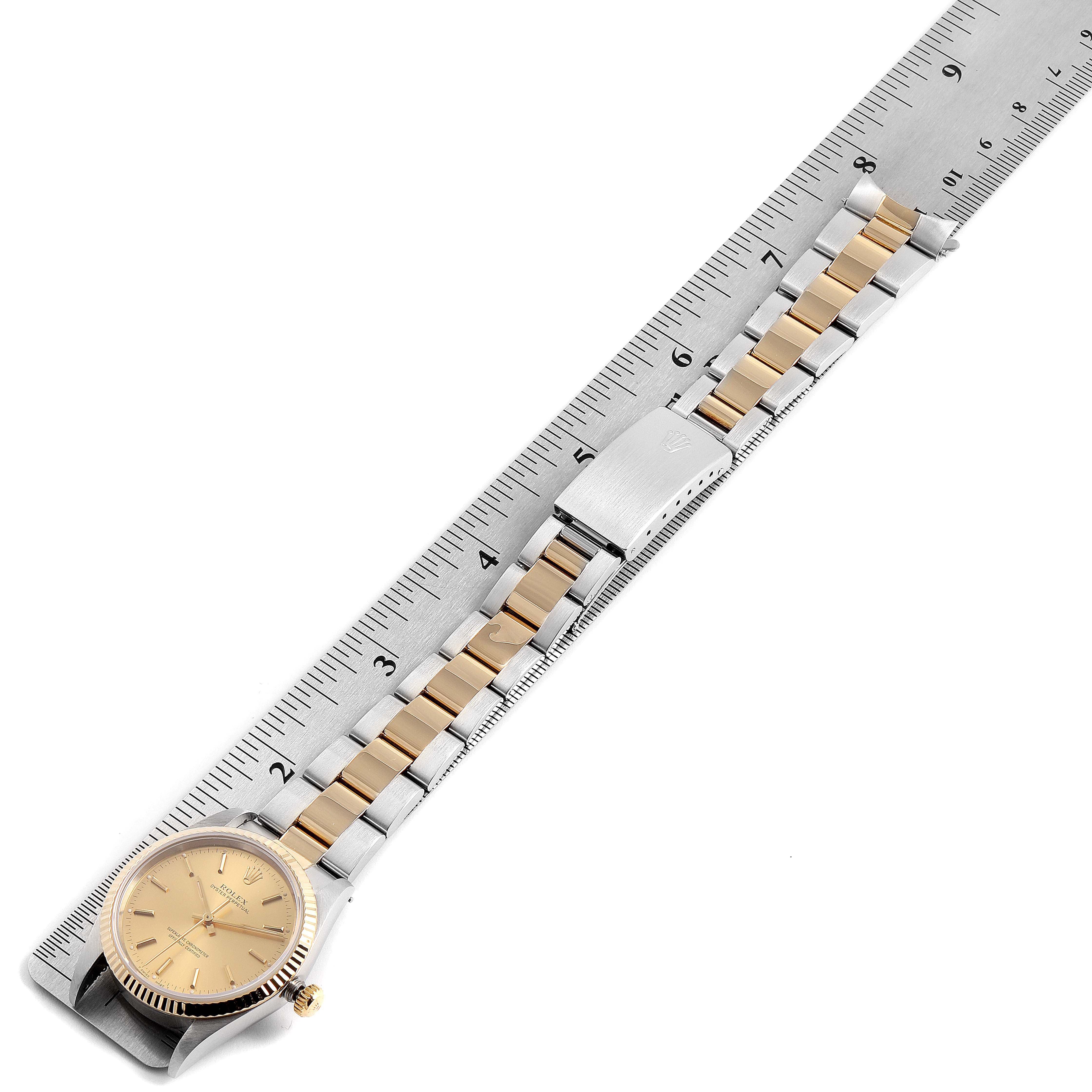 This is a top-down view of a Rolex Oyster Perpetual 14233 Men's Steel and Gold (two tone) Champagne Dial 14233 Men's Steel and Gold (two tone) Champagne Dial watch, including the dial, bezel, and bracelet, placed alongside a ruler.