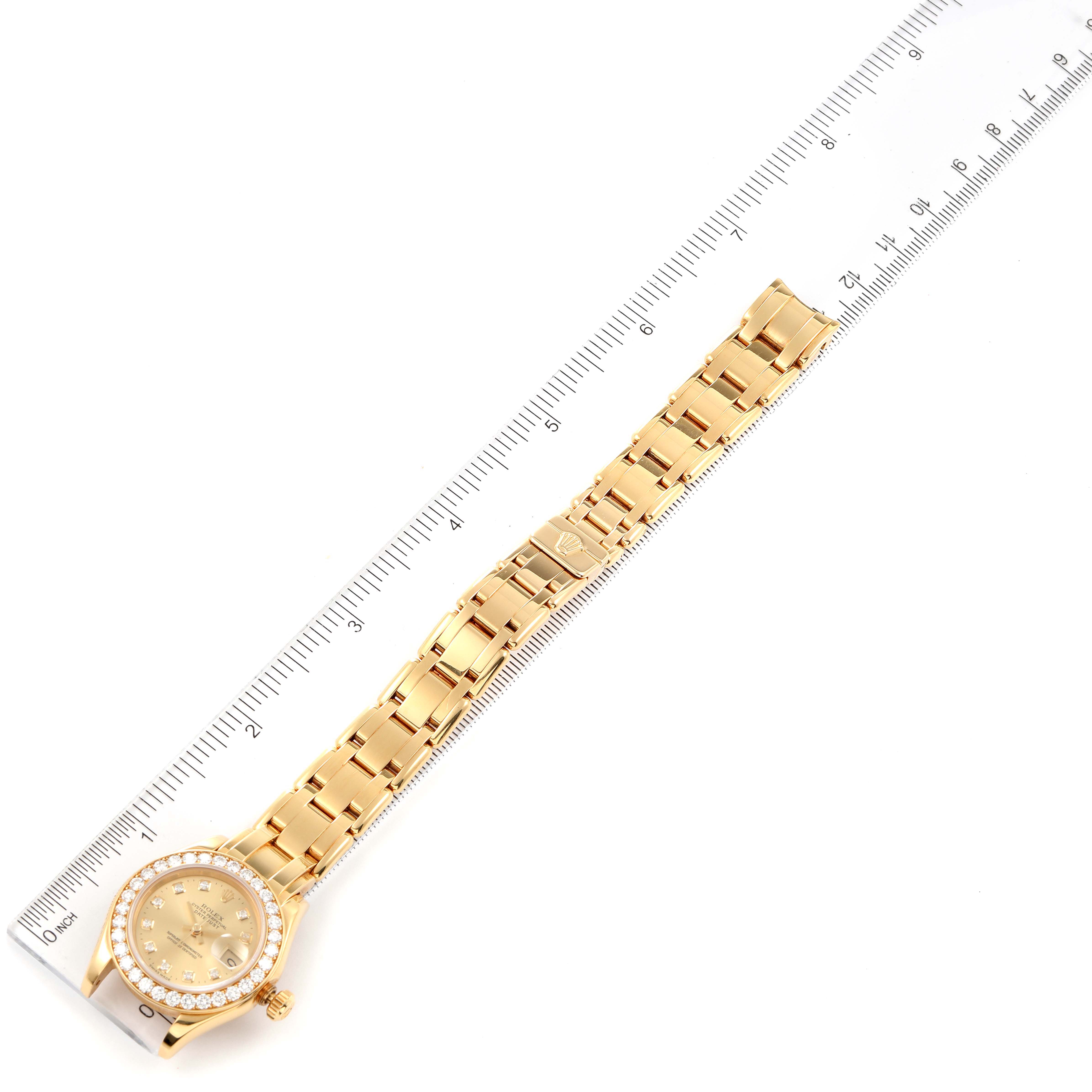 The Rolex Pearlmaster 69298 Women's Yellow Gold Champagne Dial 69298 Women's Yellow Gold Champagne Dial watch is shown at a top-down angle, displaying its full bracelet, dial, and bezel alongside a ruler for scale.