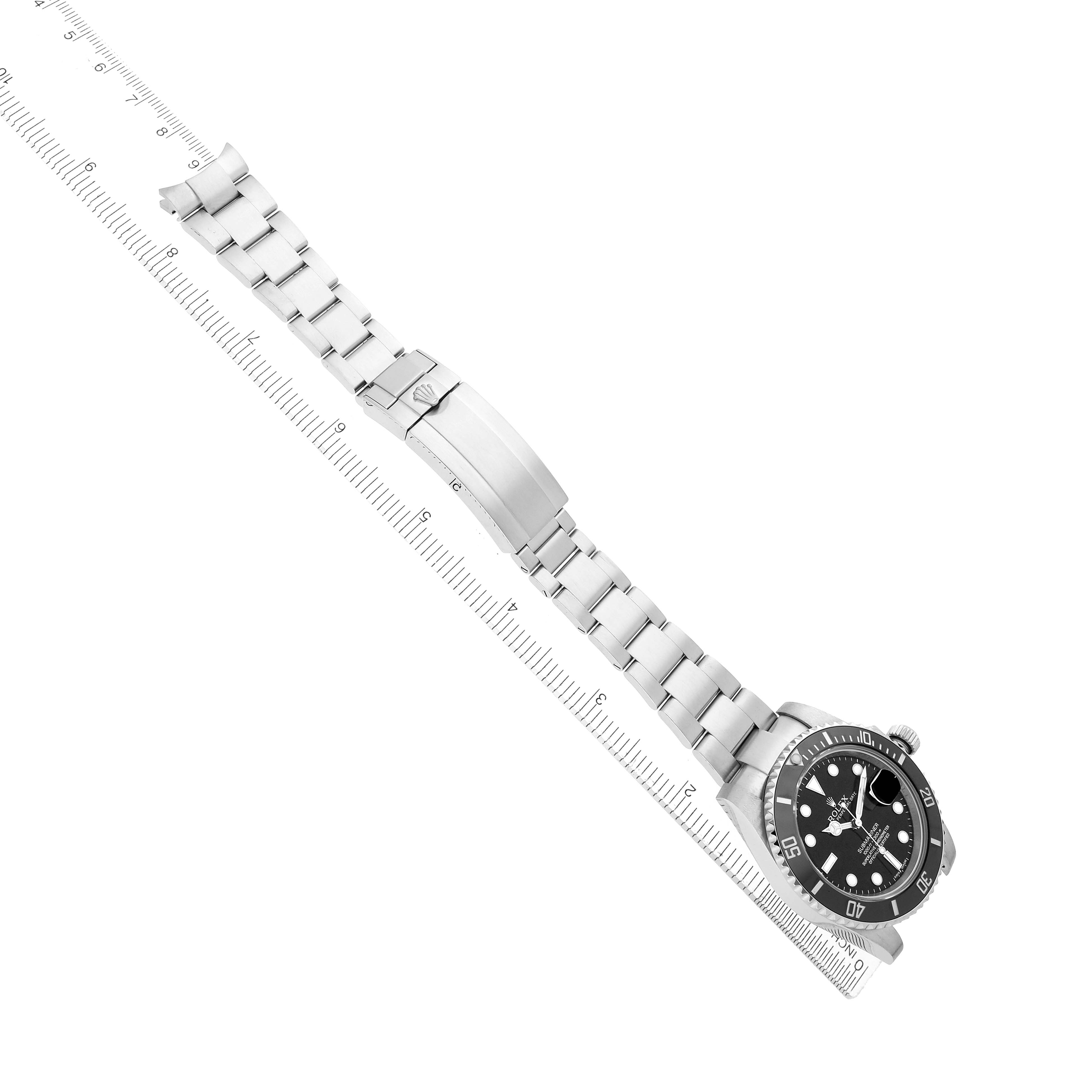The Rolex Submariner 116610 Men's Stainless Steel Black Dial is shown at an angle displaying its face, bezel, bracelet, and clasp alongside a ruler.