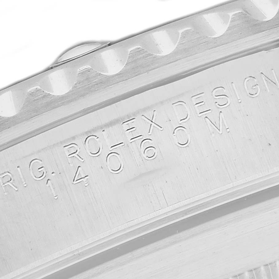 The image shows a close-up of the edge and engraved details of a Rolex Submariner 14060M Men's Stainless Steel Black Dial watch case.