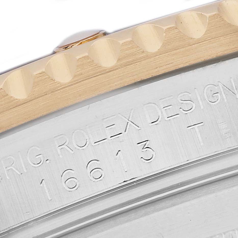 The image shows a close-up of the bezel and edge of the case with engraved text of the Rolex Submariner 16613 Men's Steel and Gold (two tone) Blue Dial.