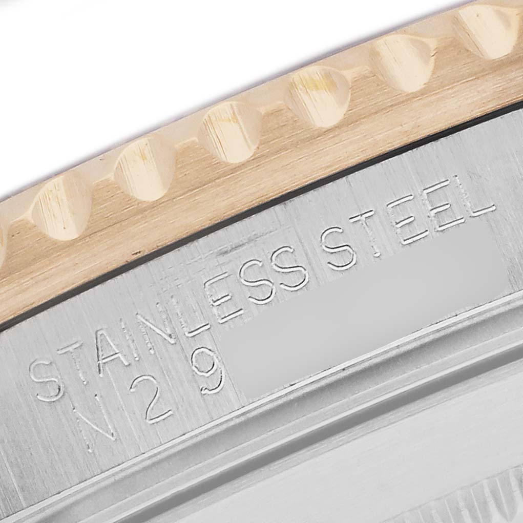 The image shows a close-up of the edge of a Rolex Submariner 16613 Men's Steel and Gold (two tone) Champagne Dial's bezel and case, highlighting the "STAINLESS STEEL" engraving.