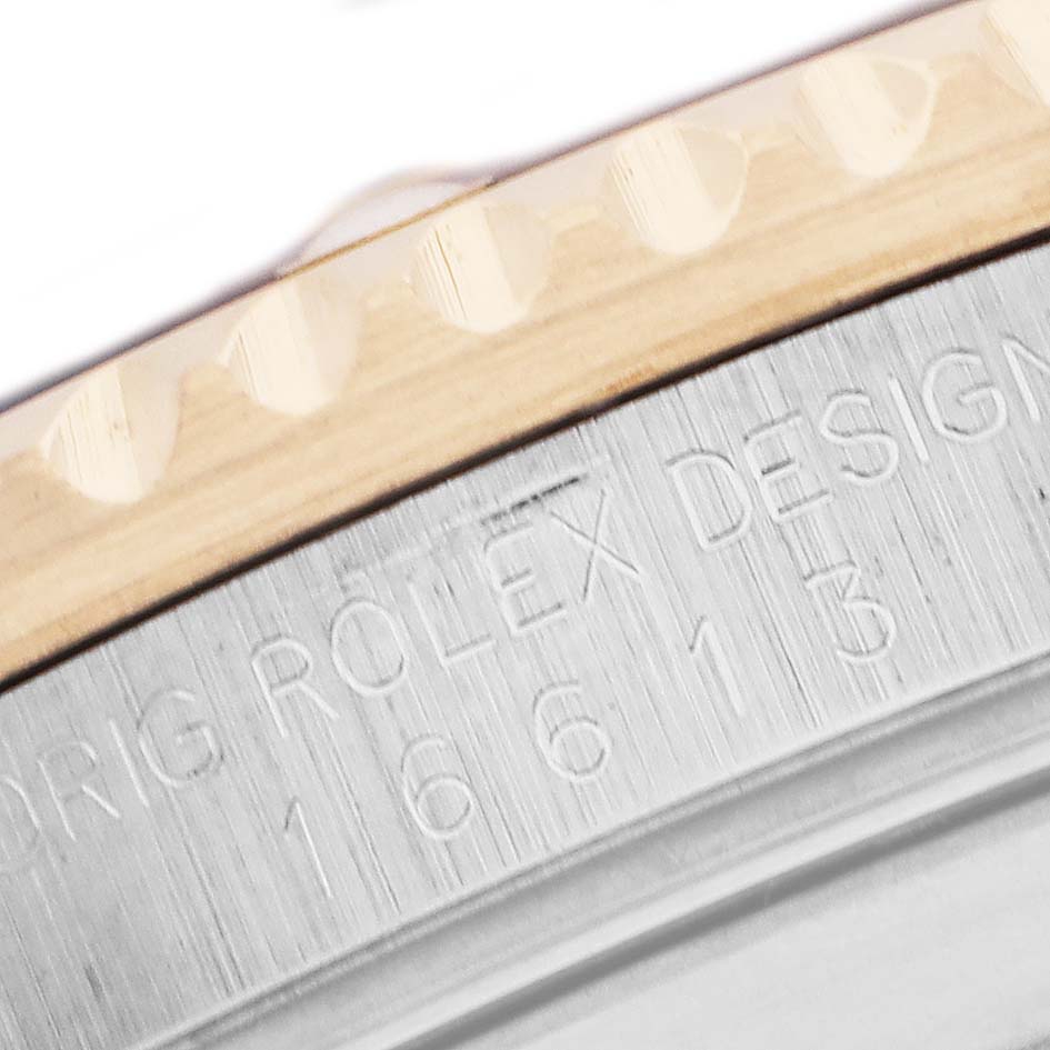 The image shows an angled close-up of the Rolex Submariner 16613 Men's Steel and Gold (two tone) Champagne Dial's bezel and engraved case edge.