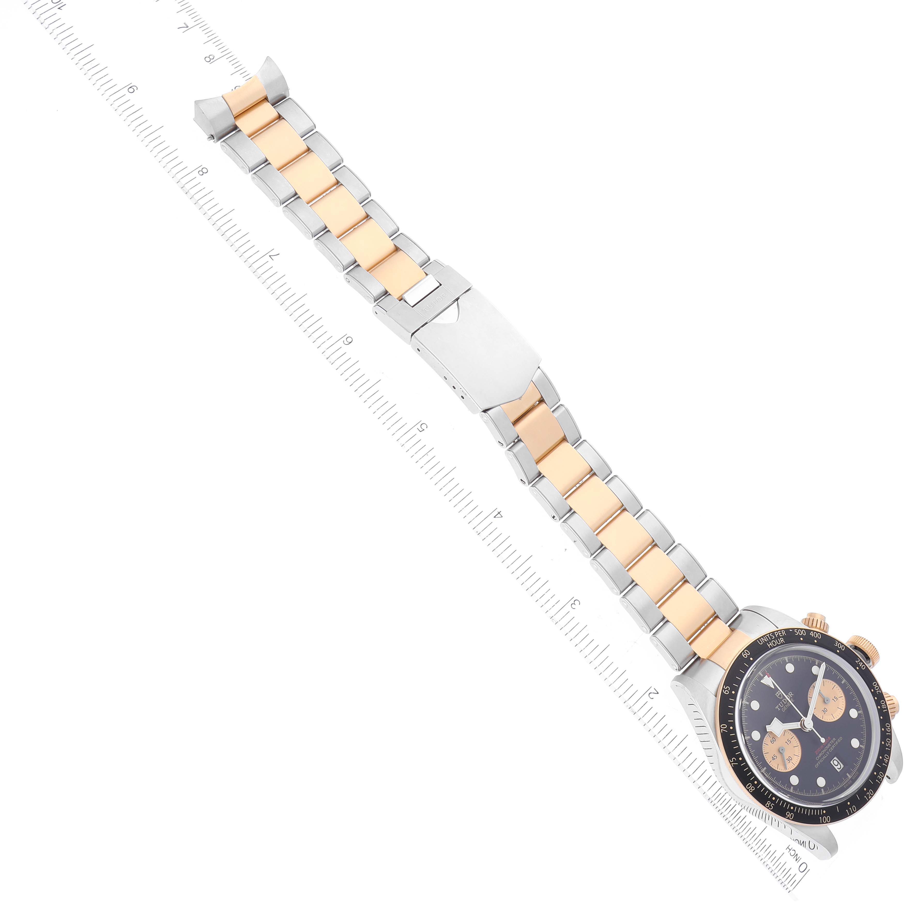 The image shows the Tudor Heritage Black Bay 79363N Men
s Steel and Gold (two tone) Black Dial 79363N Men
s Steel and Gold (two tone) Black Dial watch laid flat with its band and clasp extended alongside a ruler for measurement.