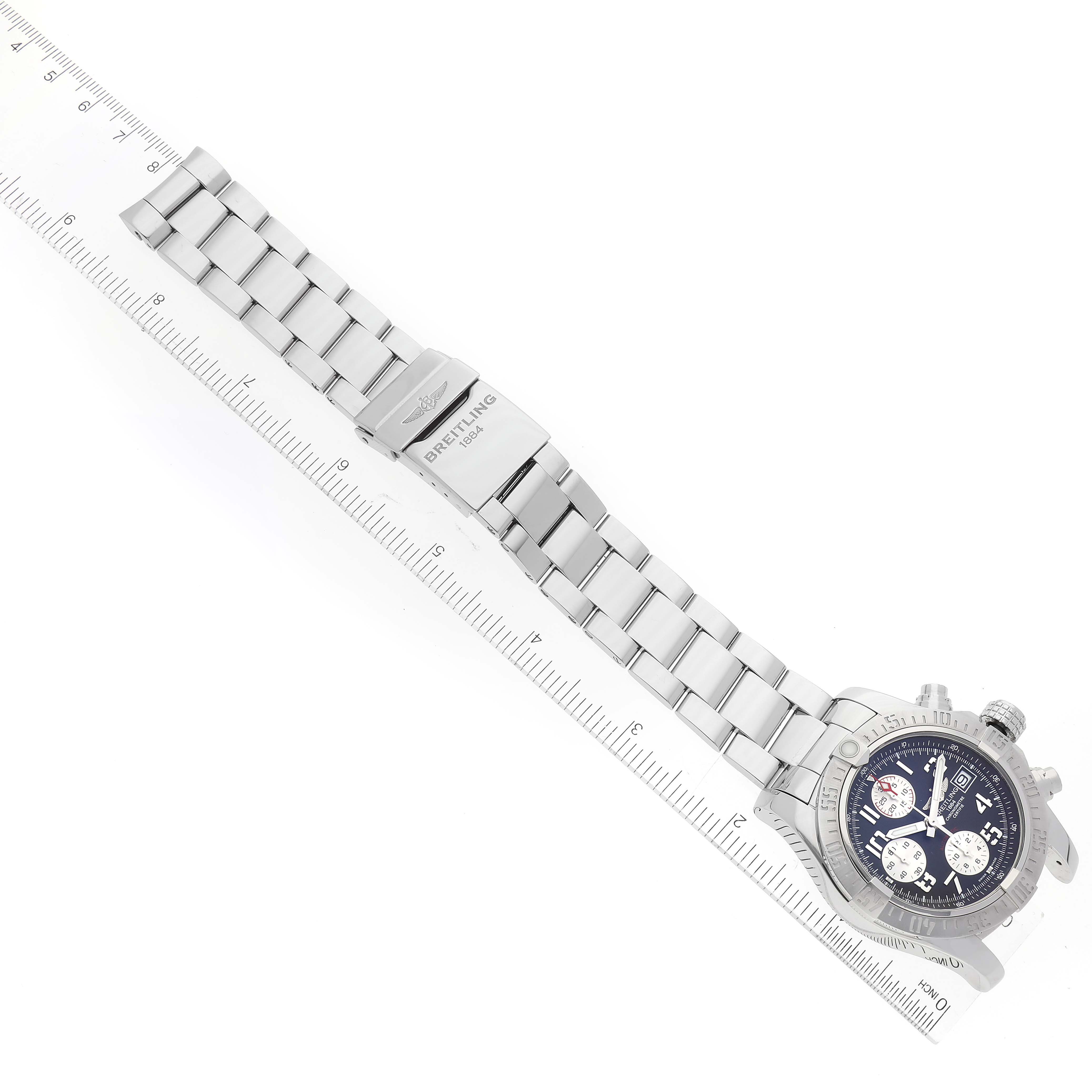 The image shows the Breitling Avenger A13381 Men's Stainless Steel Grey Dial A13381 Men's Stainless Steel Grey Dial watch at an angled top-down view, displaying the full bracelet and clasp along a ruler for scale.