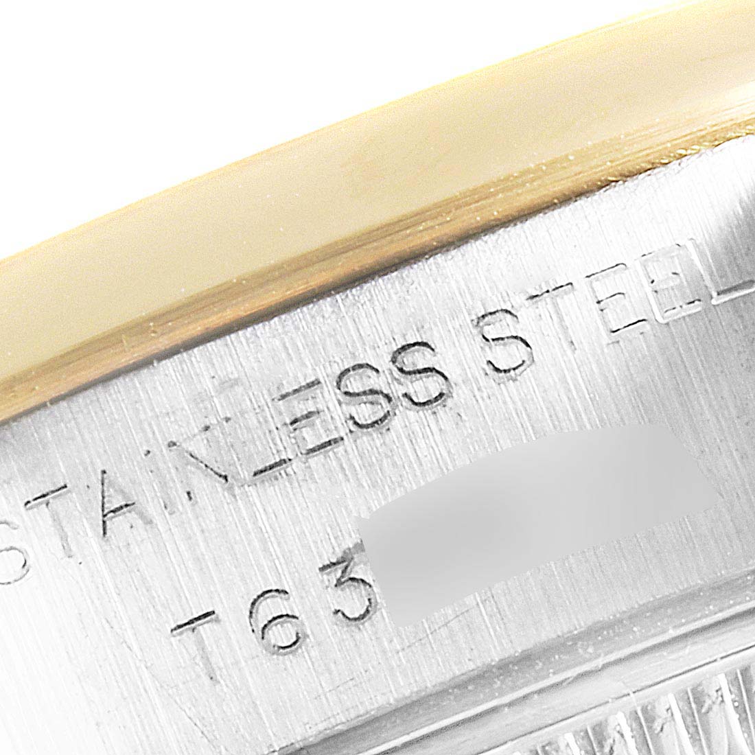 The image shows a close-up of the side of a Rolex Datejust 69163 Women's Steel and Gold (two tone) Champagne Dial 69163 Women's Steel and Gold (two tone) Champagne Dial watch, highlighting the stainless steel case and some engraved text.