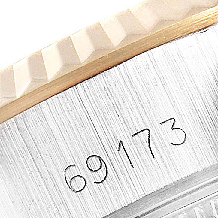 The image shows a close-up angled view of a serial number engraved on the side of a Rolex Datejust 69173 Women's Steel and Gold (two tone) Champagne Dial 69173 Women's Steel and Gold (two tone) Champagne Dial model watch's case and bezel.