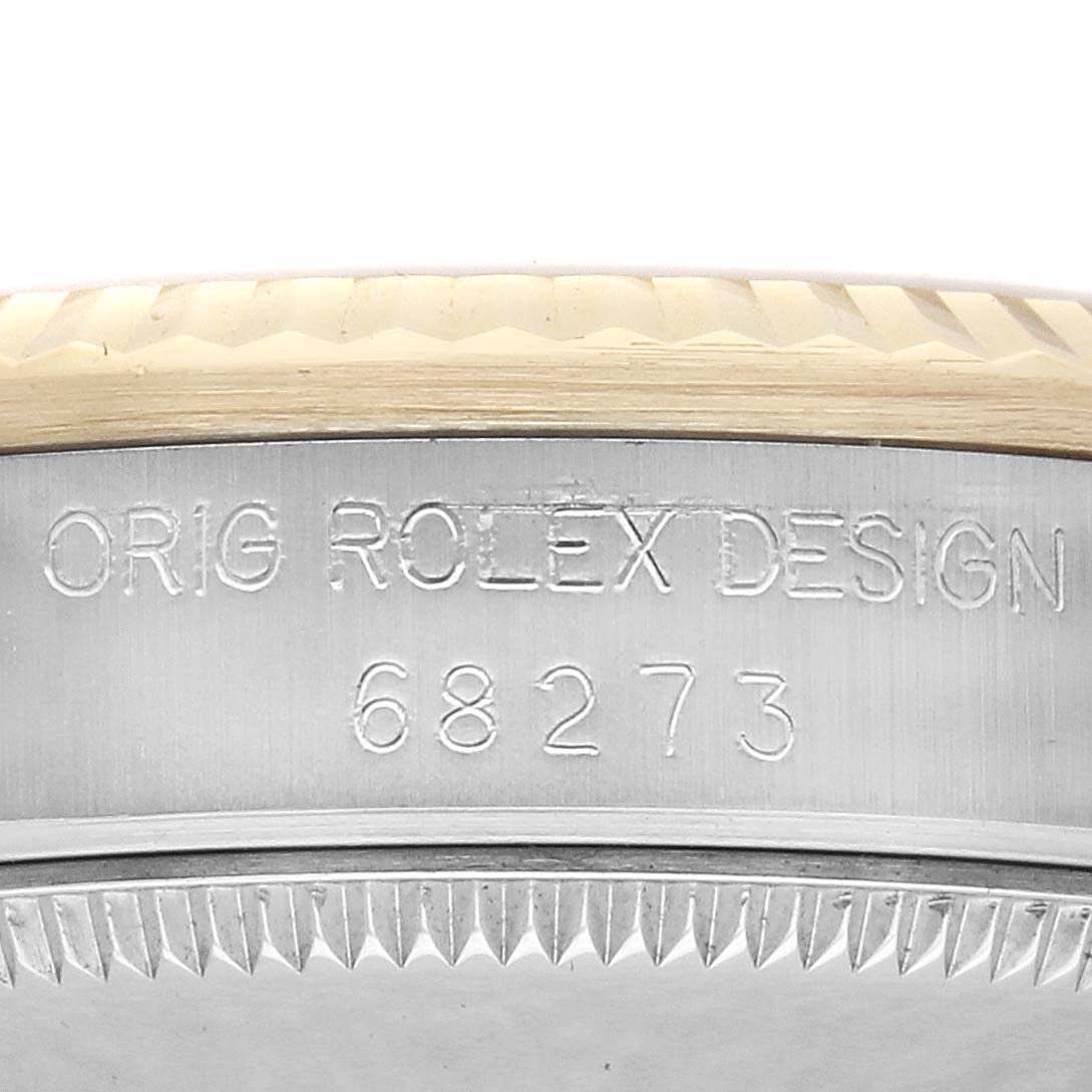The image shows the side of a Rolex Mid-Size 68273 Women
s Steel and Gold (two tone) Champagne Dial model, focusing on the bezel and engraved serial details.