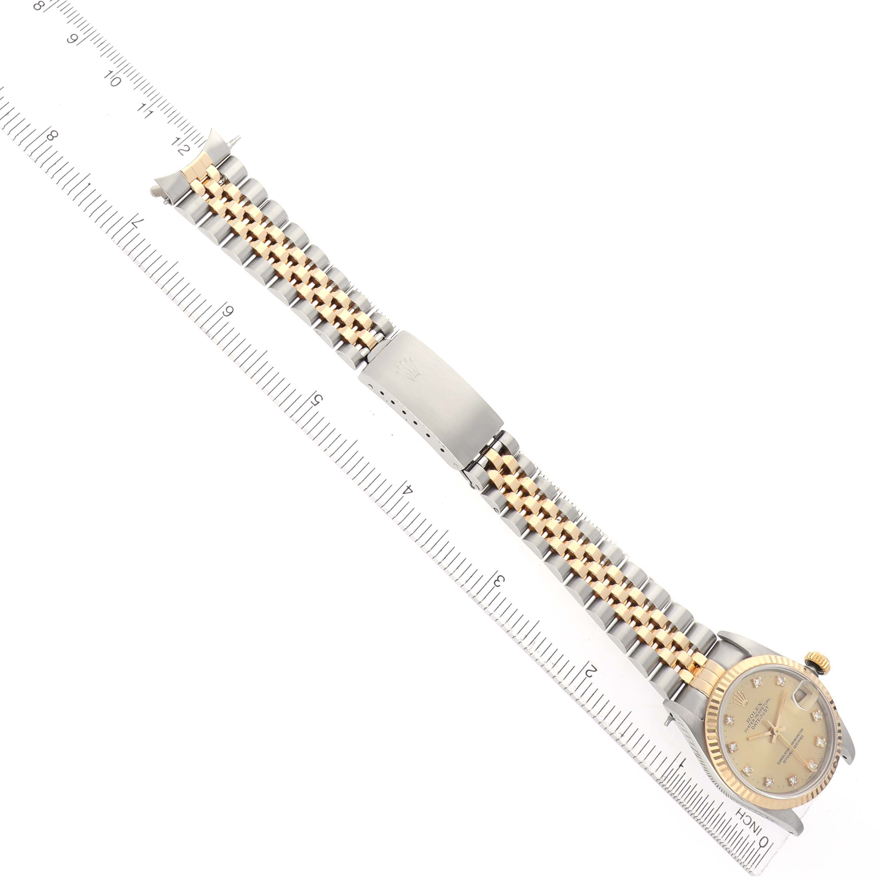The Rolex Mid-Size 68273 Women
s Steel and Gold (two tone) Champagne Dial watch is shown from a top-down angle, displaying the face, band, and clasp alongside a ruler.