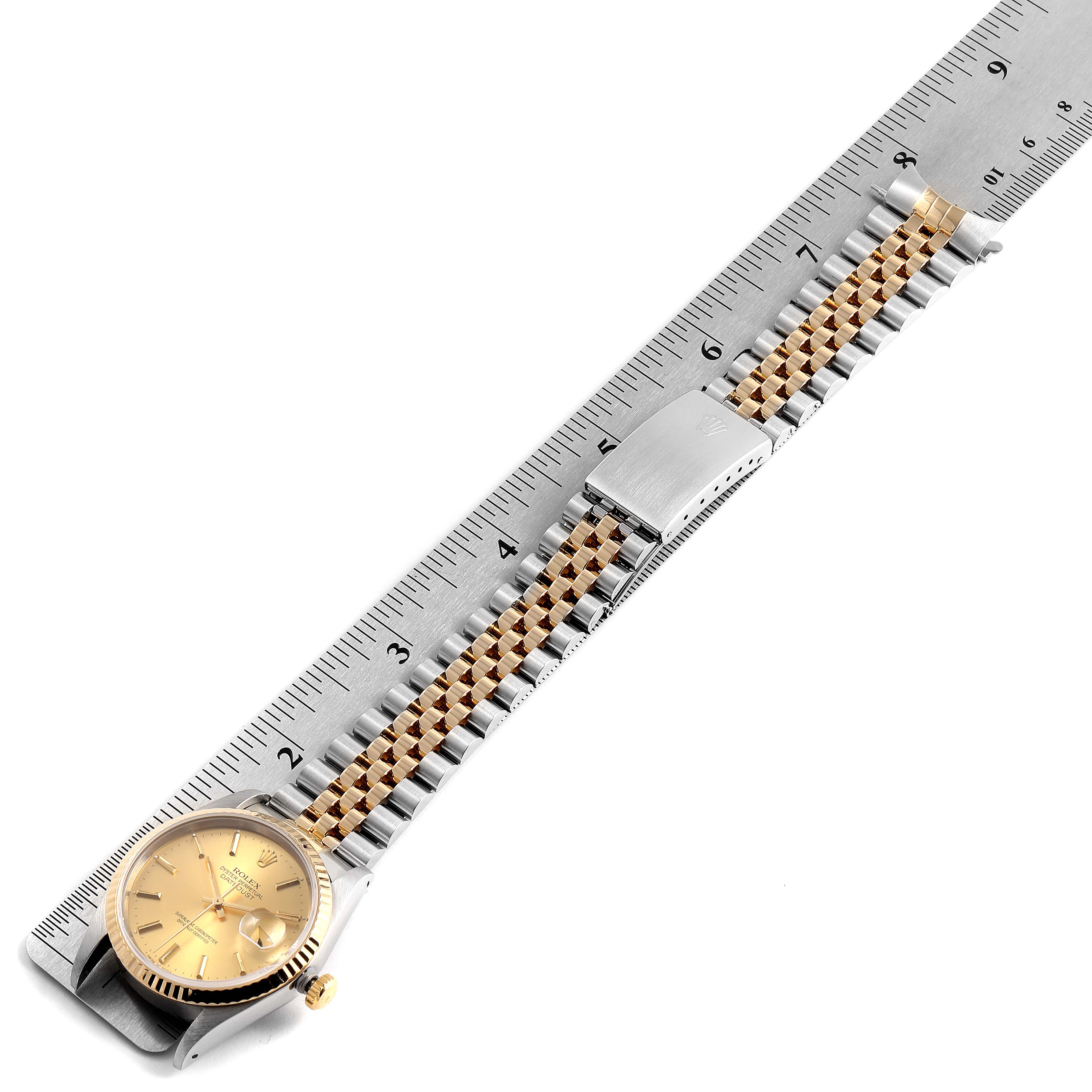The Rolex Datejust 16233 Men's Steel and Gold (two tone) Champagne Dial 16233 Men's Steel and Gold (two tone) Champagne Dial watch is shown from a top-down angle, displaying the face, bracelet, and clasp alongside a ruler.