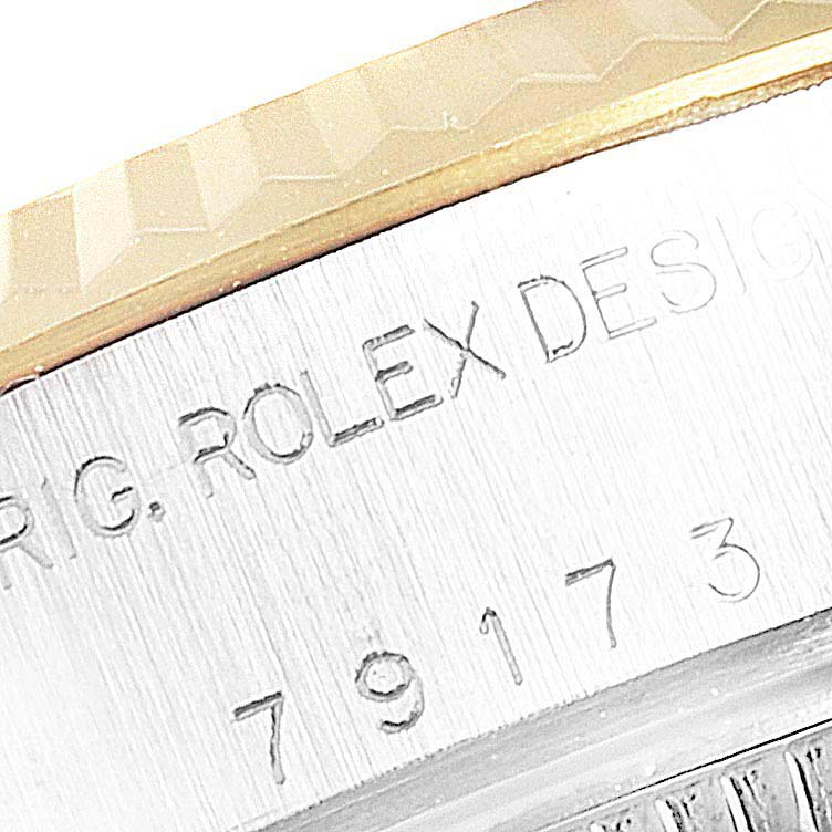 This image shows a close-up of the engraved side of the Rolex Datejust 79173 Women's Steel and Gold (two tone) Champagne Dial 79173 Women's Steel and Gold (two tone) Champagne Dial watch, featuring the serial number and "ROLEX DESIGN."