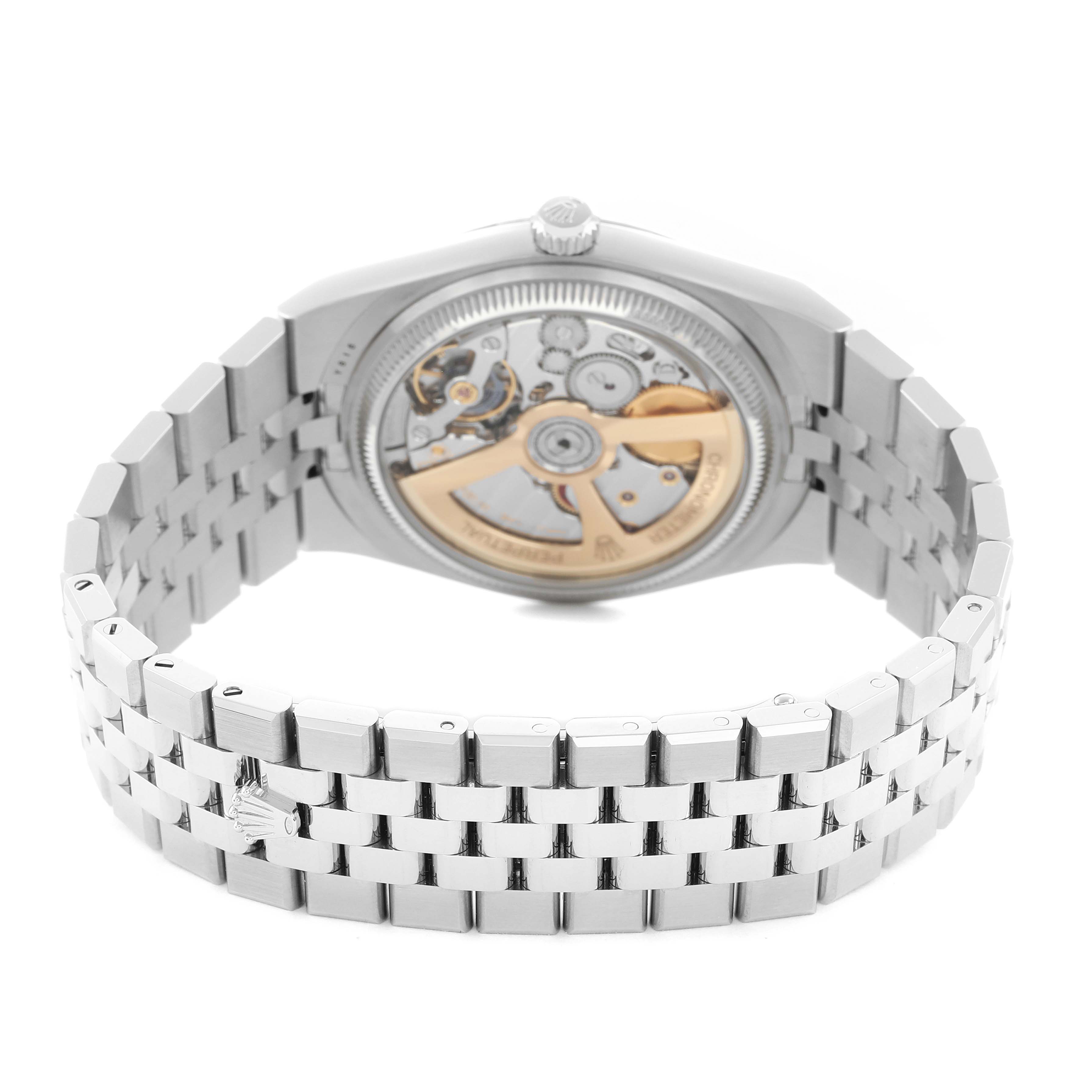 The image shows the back of a Rolex Land-Dweller watch, detailing the movement and bracelet from a rear angle.