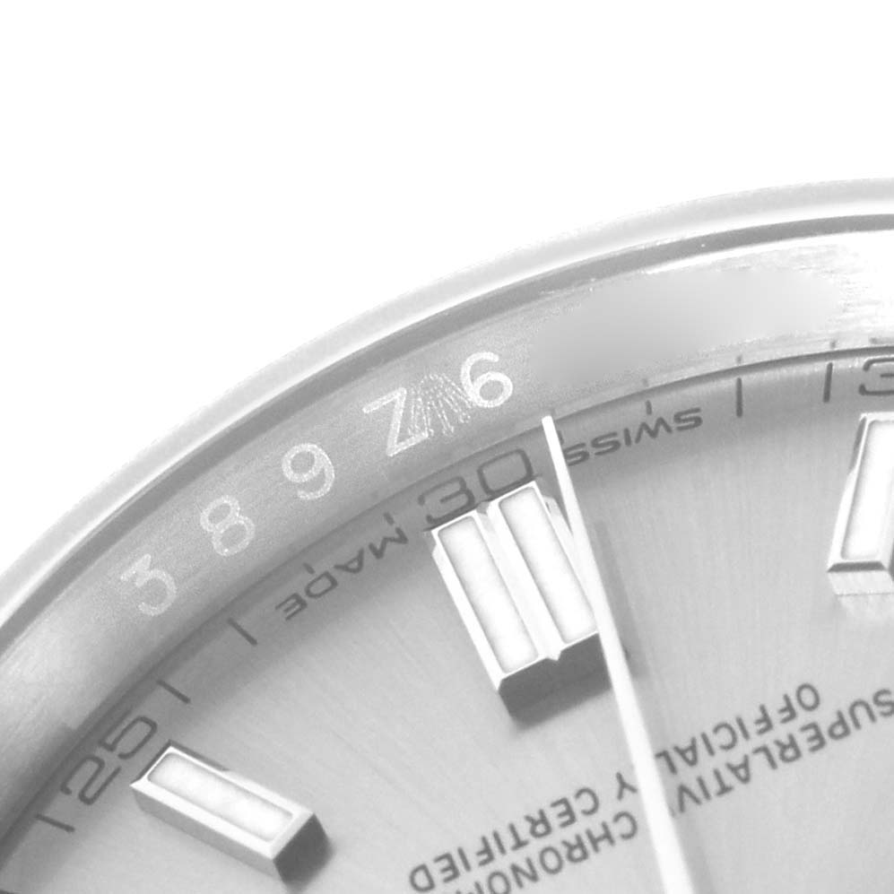 The image shows a close-up of the dial edge and markers of a Rolex Oyster Perpetual 116000 Men's Stainless Steel Silver Dial watch, emphasizing the numerals and indices.