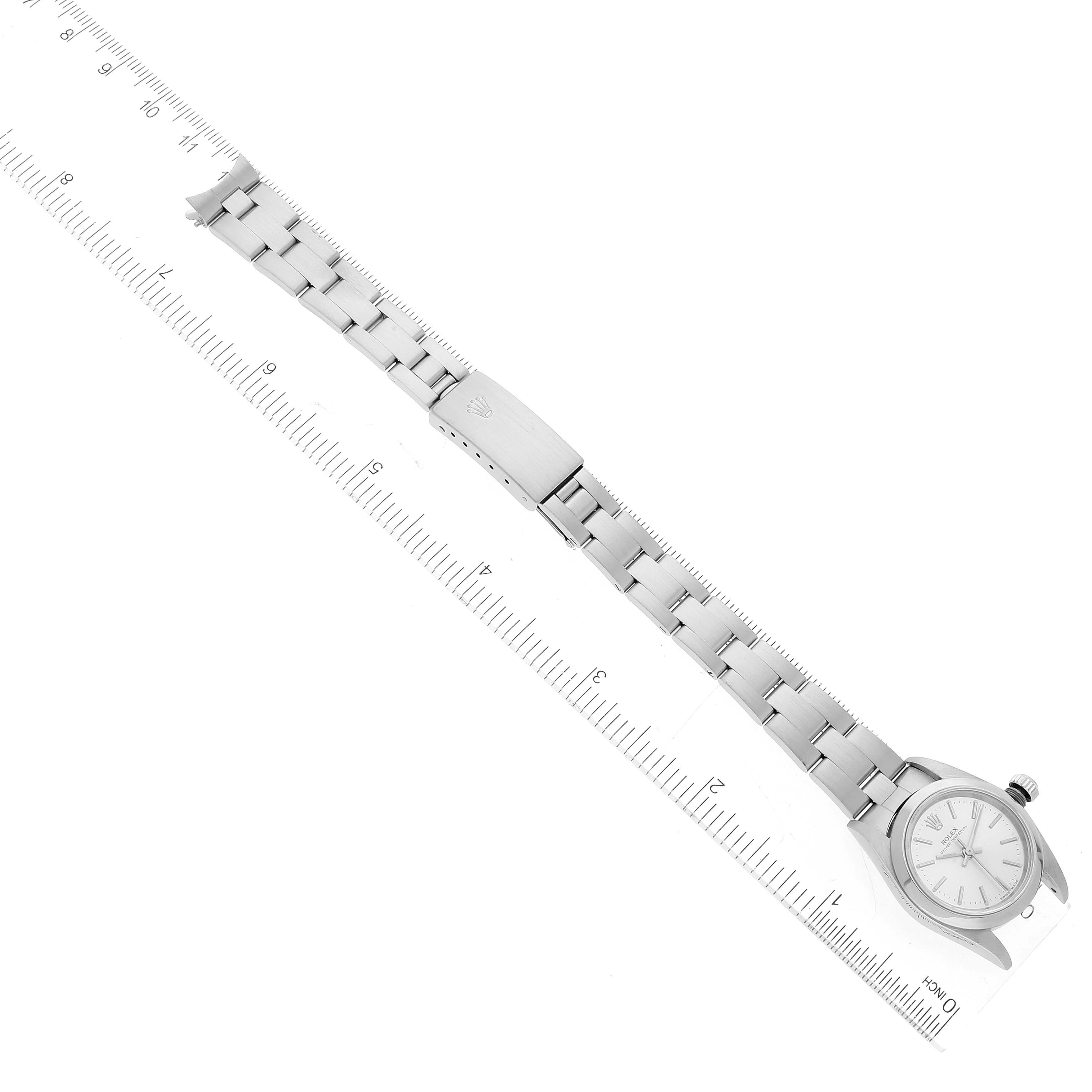 This image shows a top view of a Rolex Oyster Perpetual 76080 Women
s Stainless Steel Silver Dial 76080 Women
s Stainless Steel Silver Dial watch, with its full metal bracelet placed along a ruler.