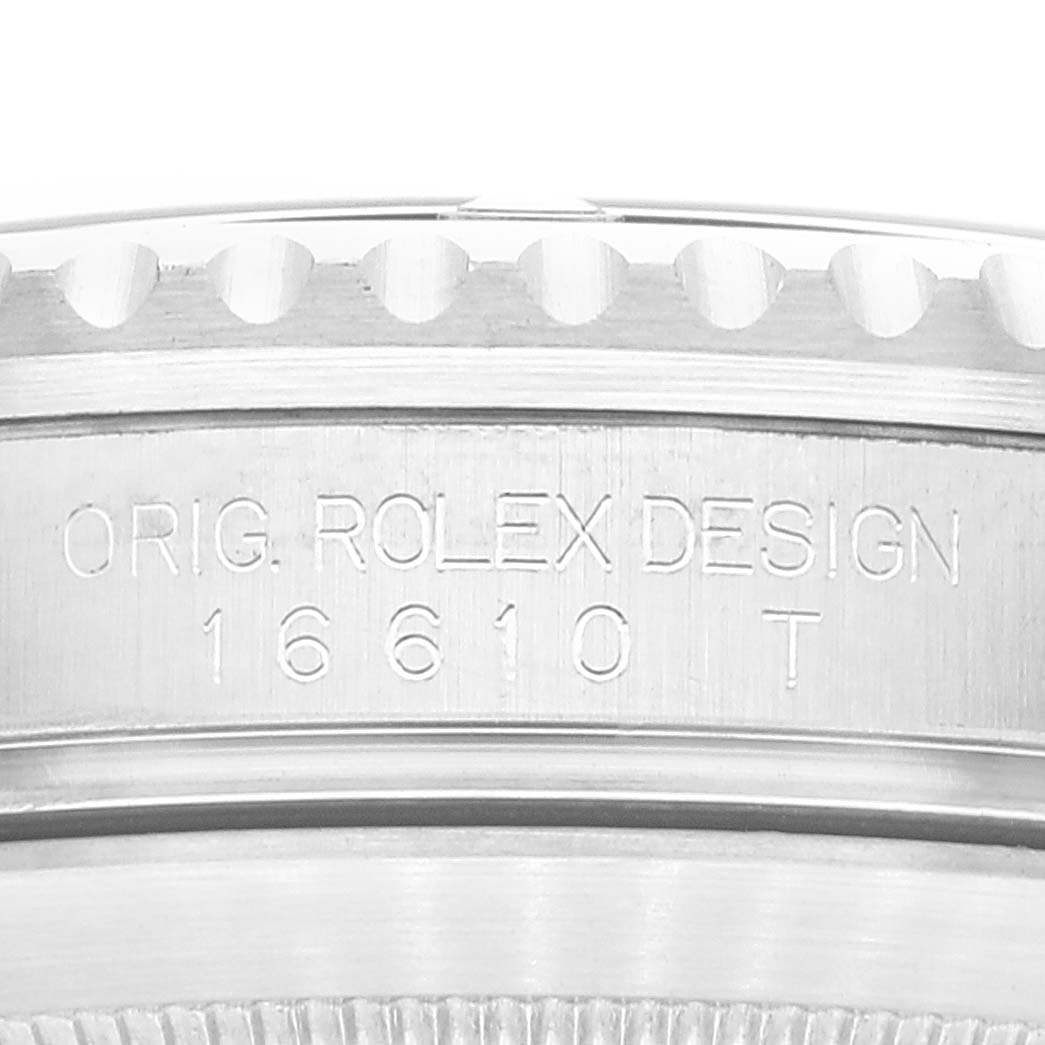 This image shows a close-up of the side of a Rolex Submariner 16610 Men's Stainless Steel Black Dial 16610 Men's Stainless Steel Black Dial watch case, featuring the model number "16610 T" and "ORIG. ROLEX DESIGN" engraving.