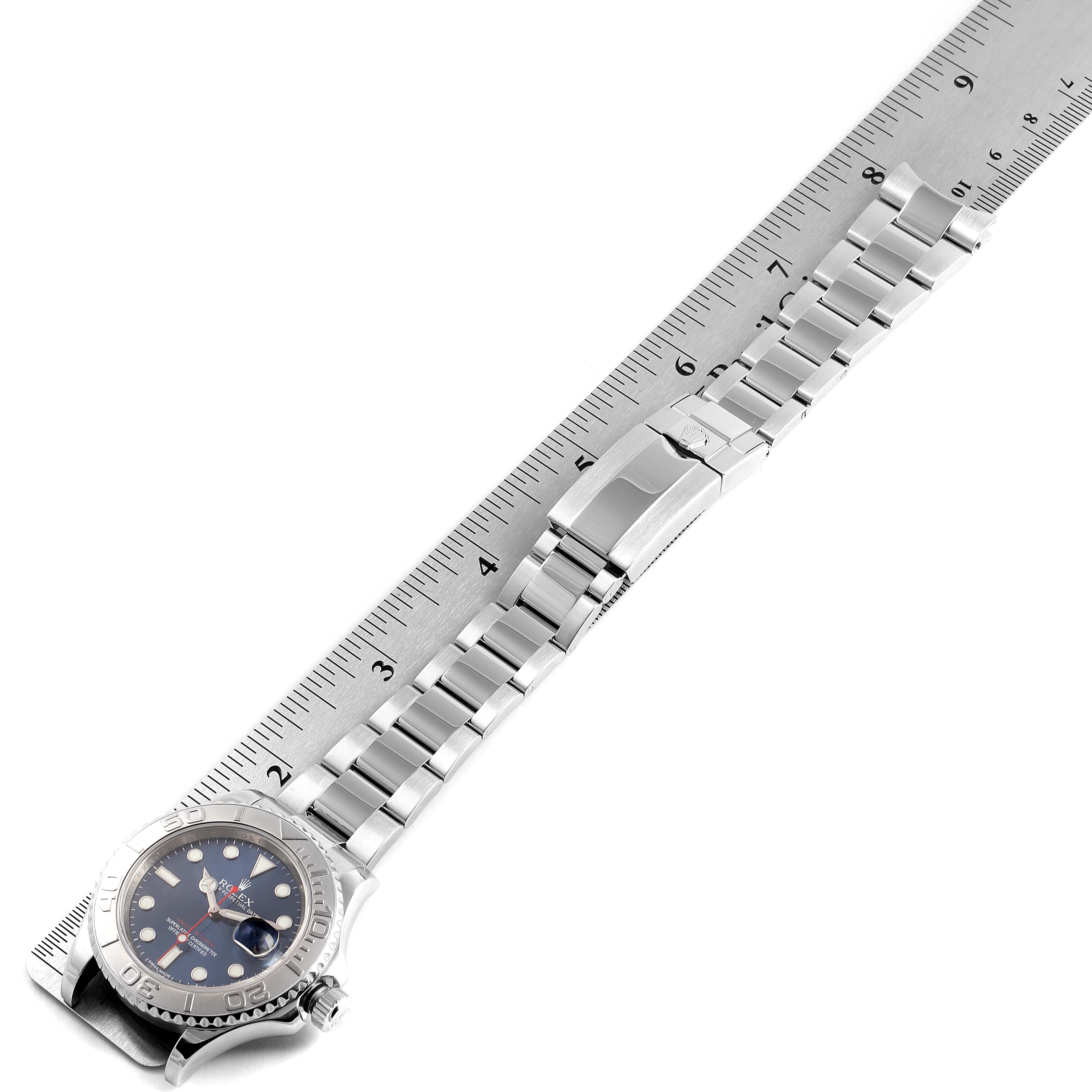 The Rolex Yacht-Master 116622 Women's Stainless Steel Blue Dial 116622 Women's Stainless Steel Blue Dial watch is shown from an angled top view, displaying its face, metal bracelet, and clasp positioned on a ruler.