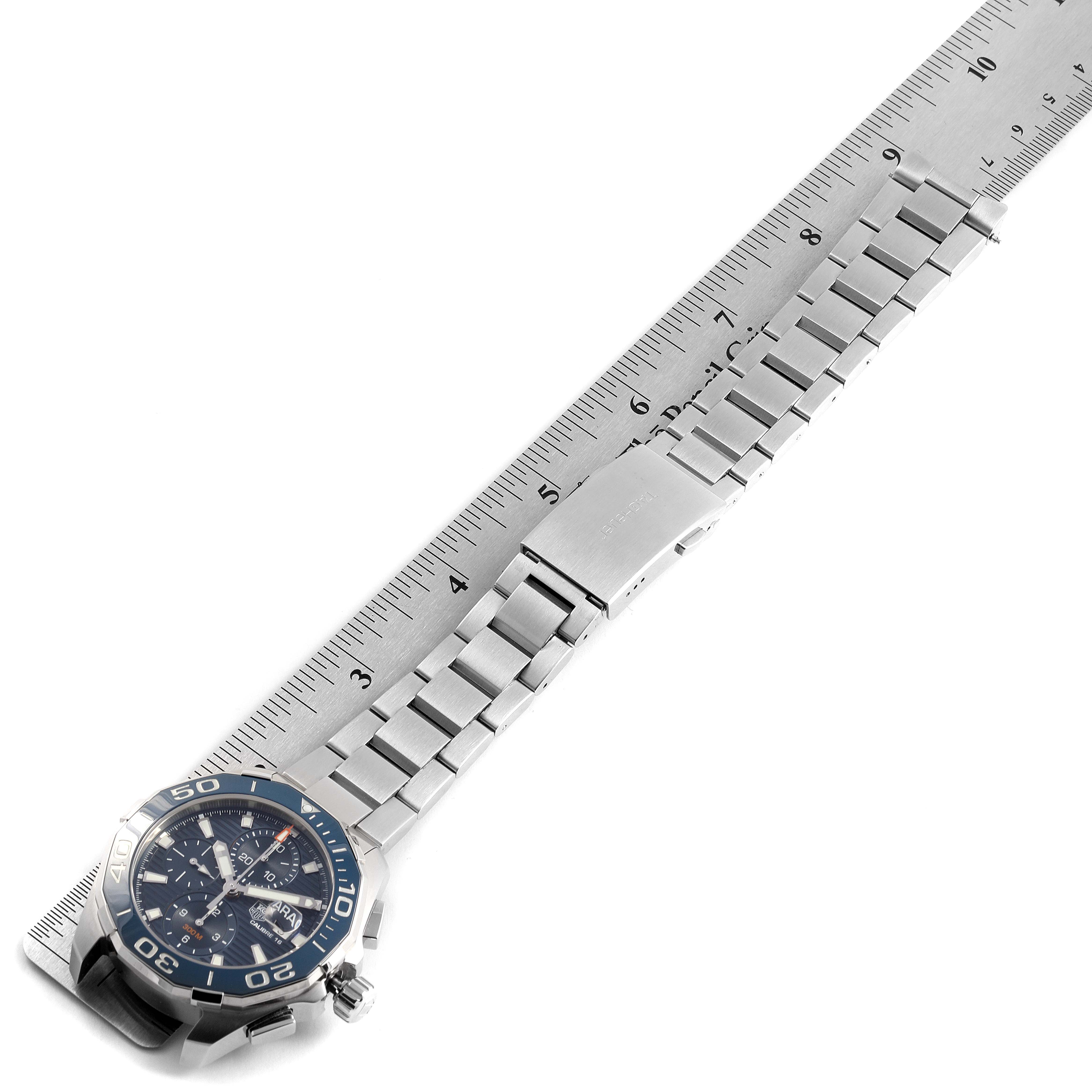This image shows a Tag Heuer Aquaracer CAY211B.BA0927 Men's Stainless Steel Blue Dial CAY211B.BA0927 Men's Stainless Steel Blue Dial watch positioned diagonally with its stainless steel bracelet placed alongside a ruler.