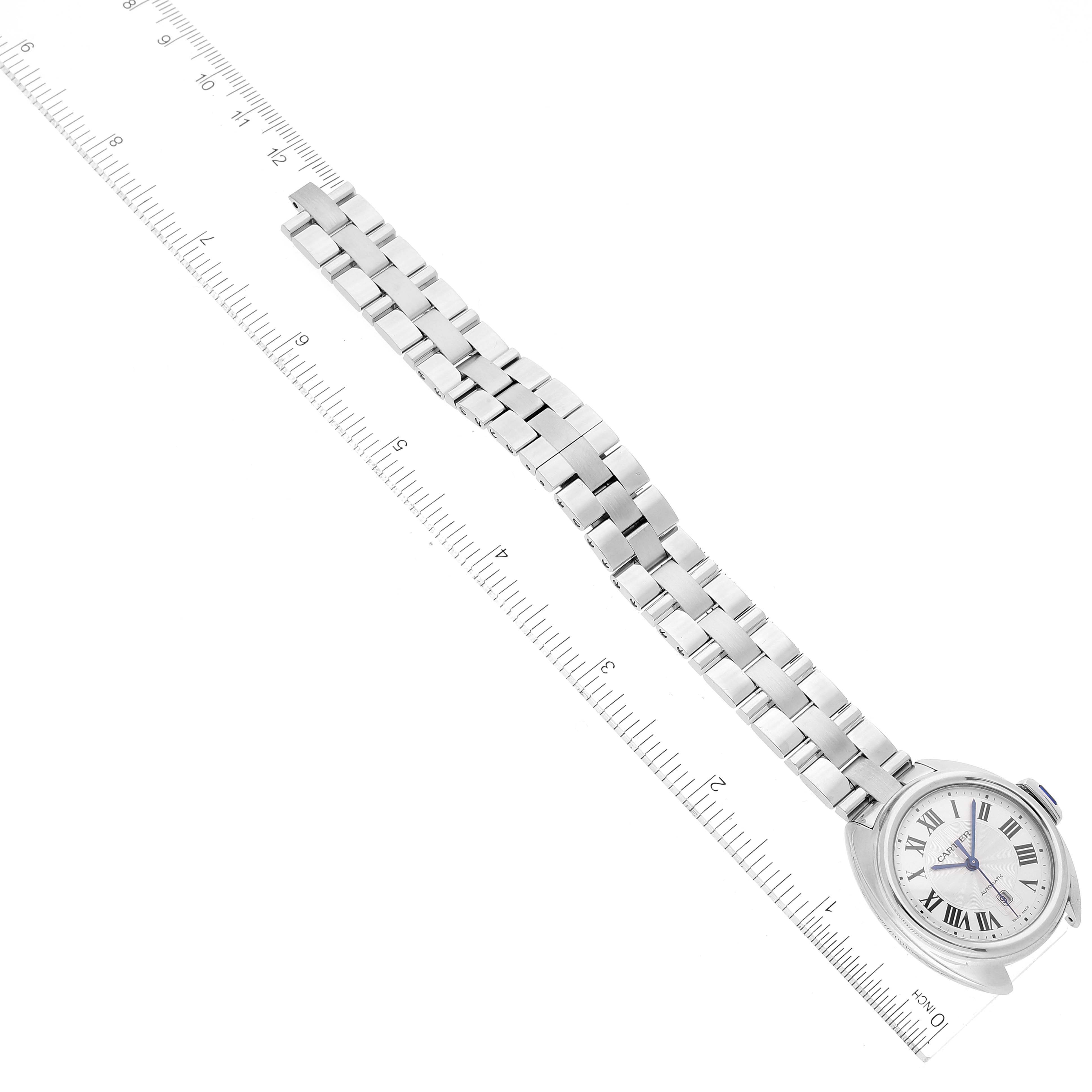 The image shows a top-down view of a Cartier Cle WSCL0005 Women's Stainless Steel Blue Dial WSCL0005 Women's Stainless Steel Blue Dial watch, displaying its face and metal bracelet alongside a measuring ruler.