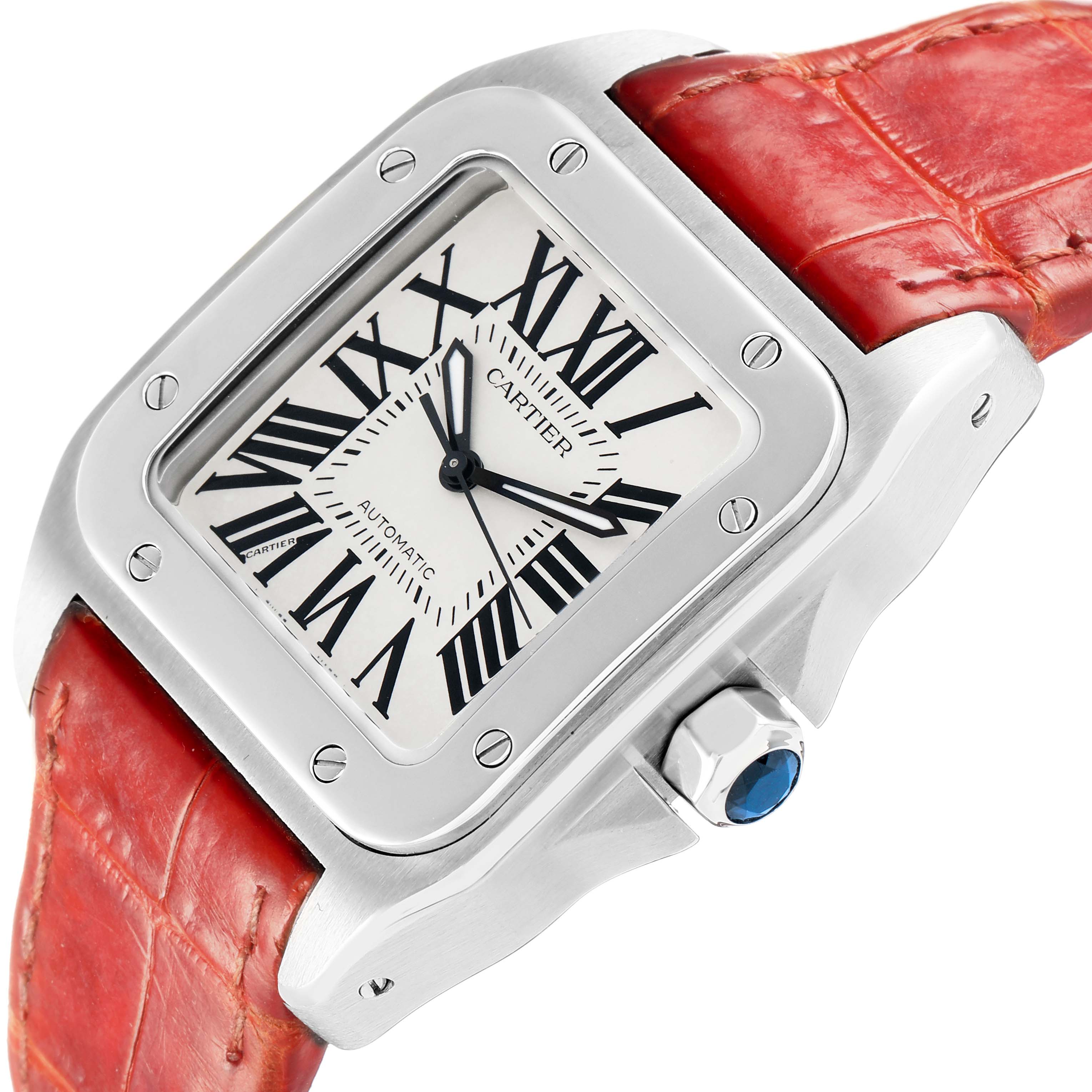 The Cartier Santos W20126X8 Men
s Stainless Steel Silver Dial watch is shown at an angled view, featuring its dial, red strap, and crown with a blue cabochon.